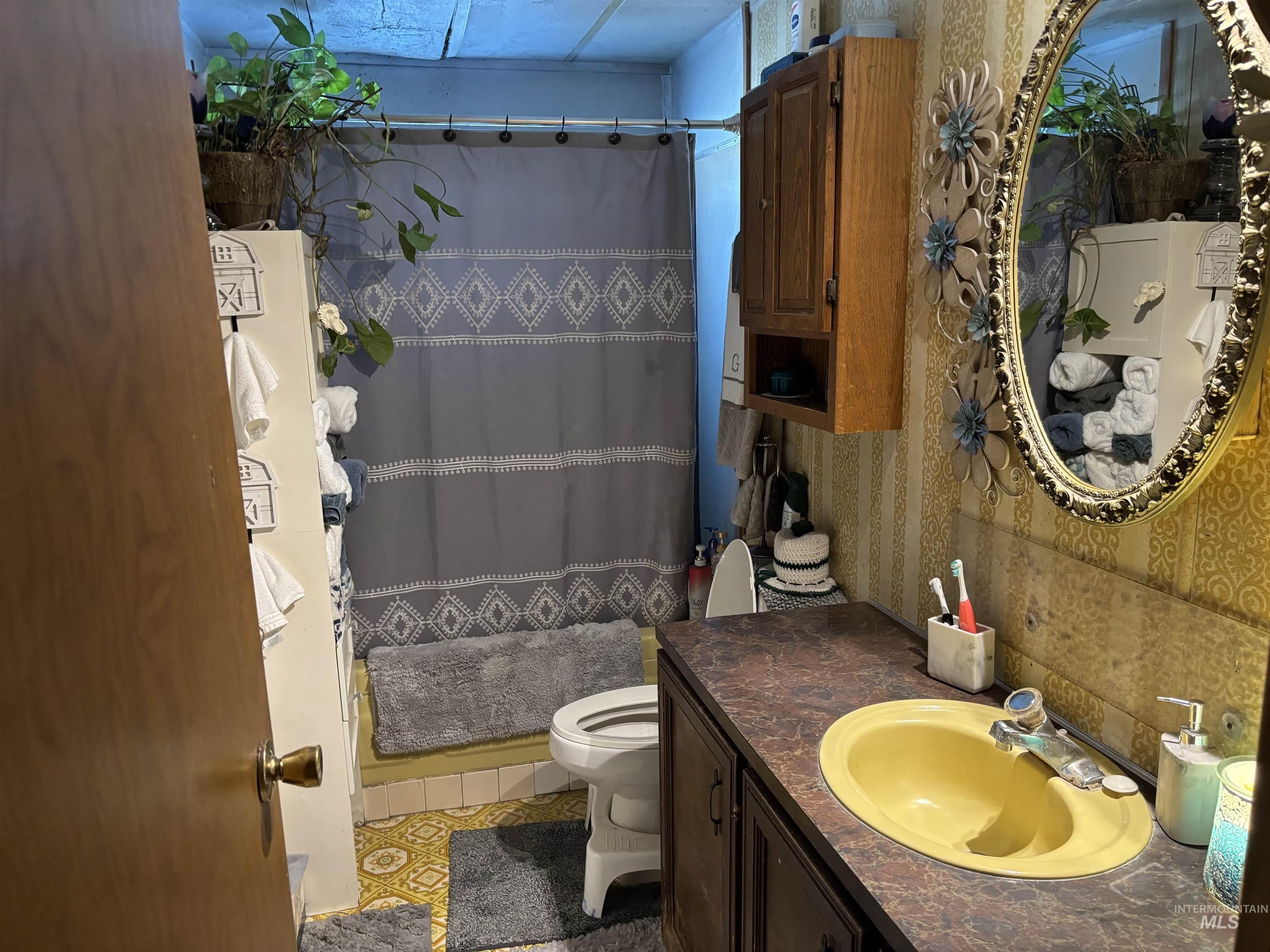 Full bathroom with a shower with curtain, light tile patterned floors, vanity, and wallpapered walls
