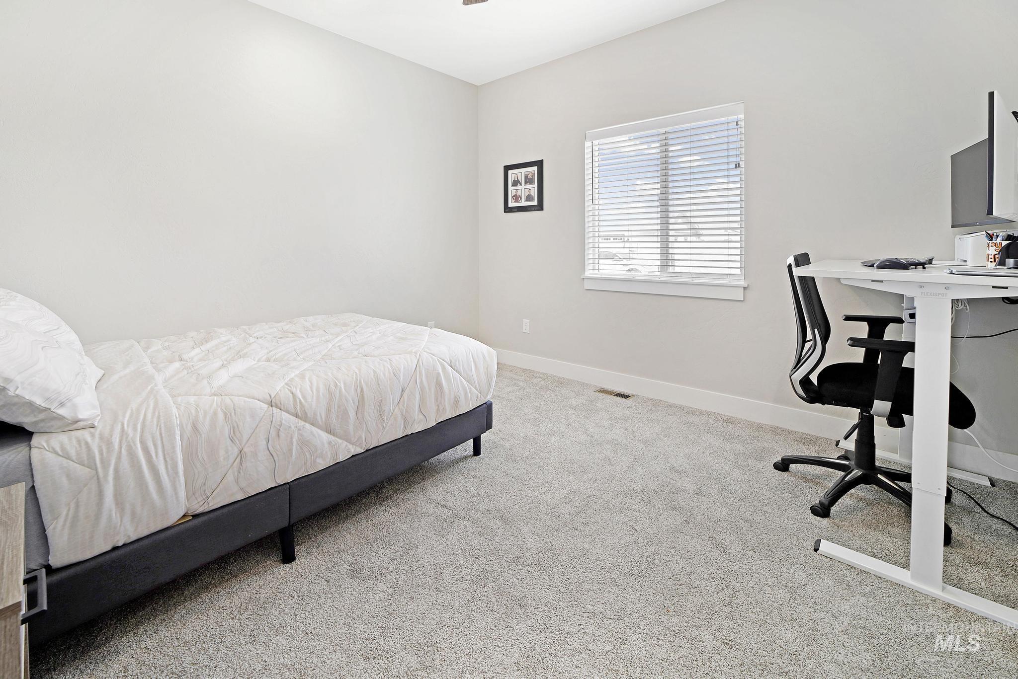 Bedroom with light colored carpet, a ceiling fan, and a desk