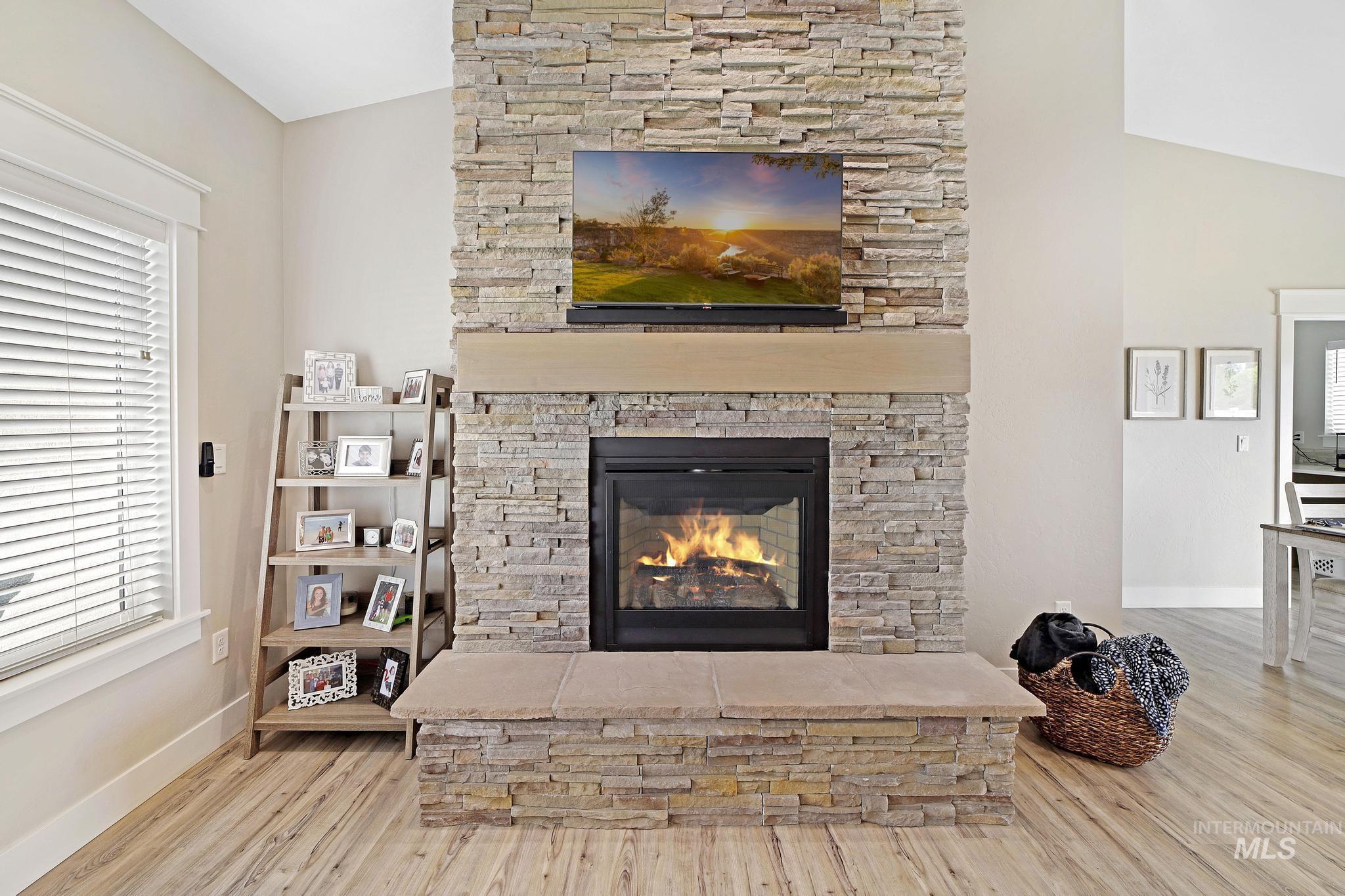 Living room featuring light wood-style floors, a fireplace, and vaulted ceiling