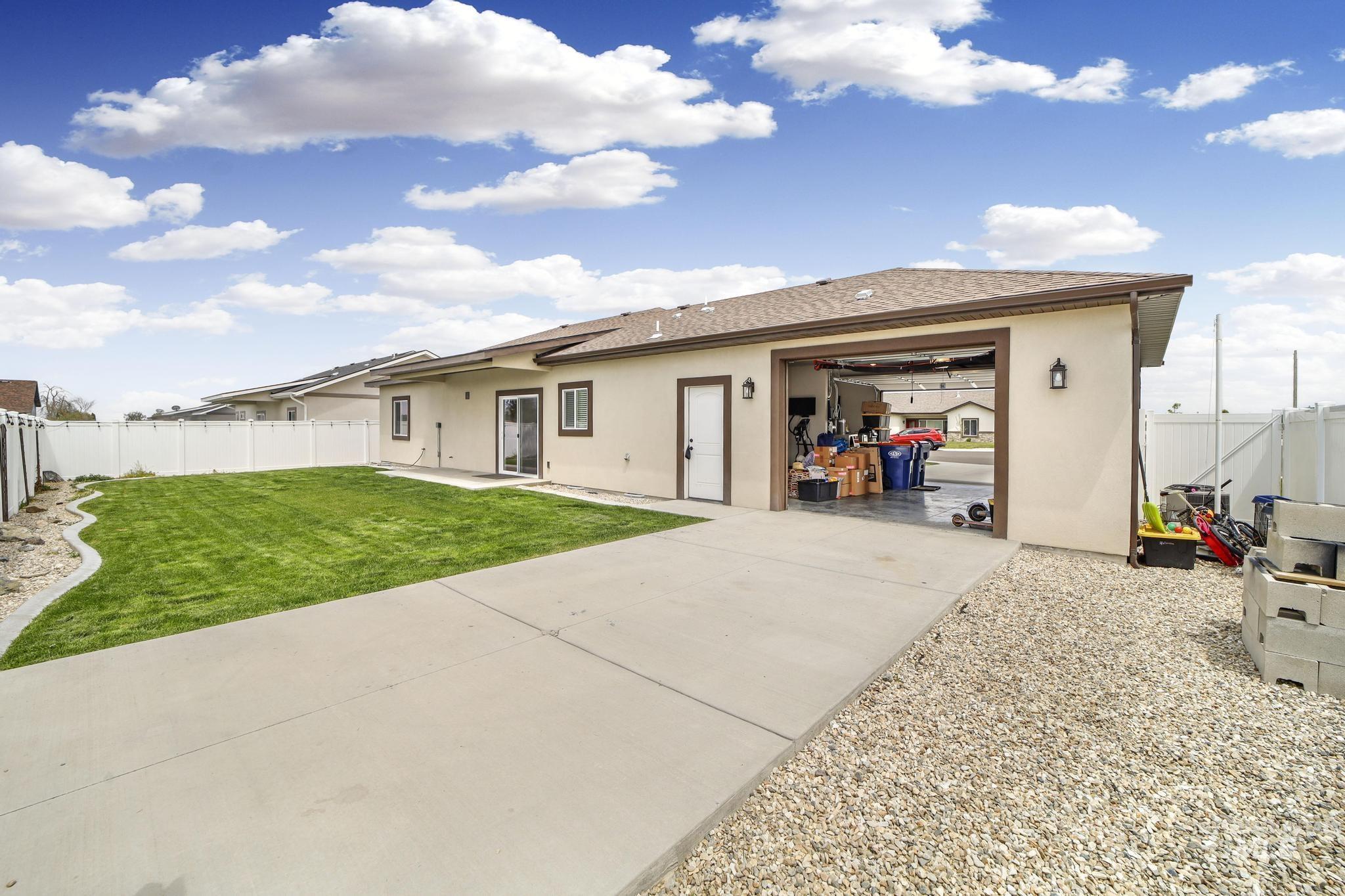 Back of house featuring stucco siding, a fenced backyard, a patio, driveway, and an attached garage