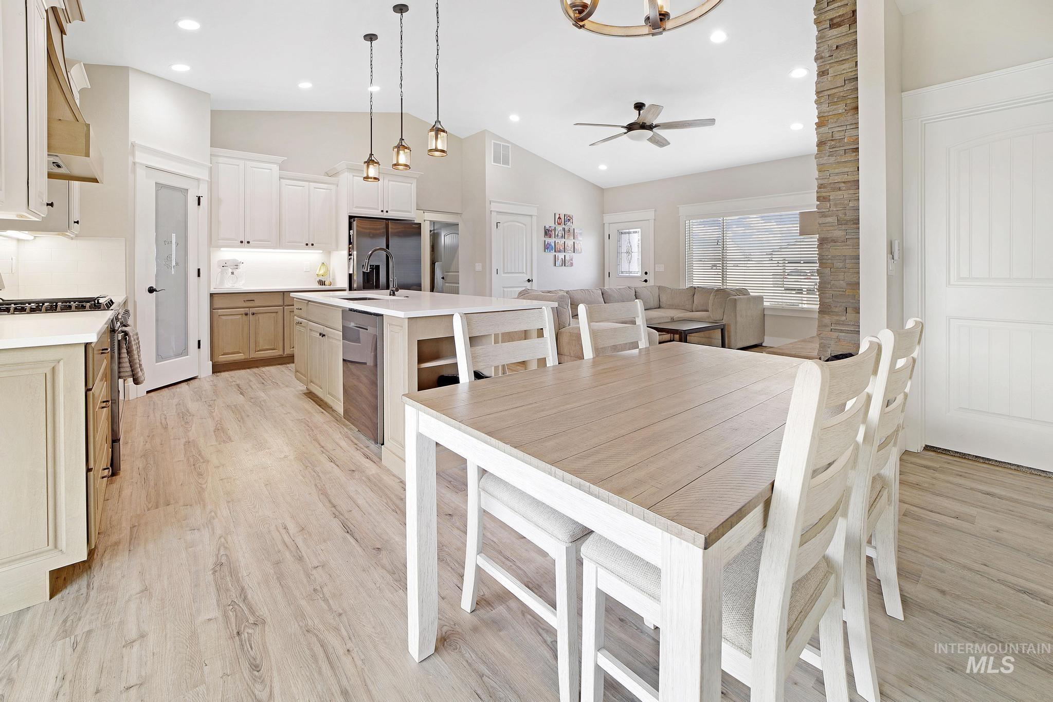 Dining room with light wood-type flooring, a ceiling fan, recessed lighting, high vaulted ceiling, and a chandelier