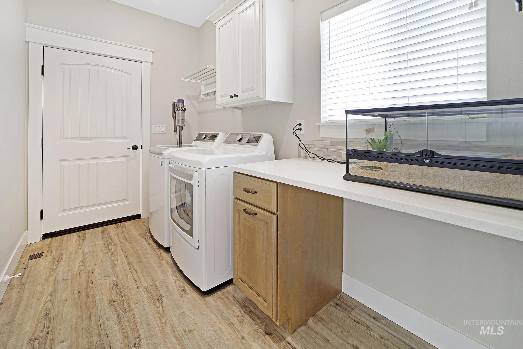 Washroom featuring light wood-type flooring, washing machine and clothes dryer, and cabinet space
