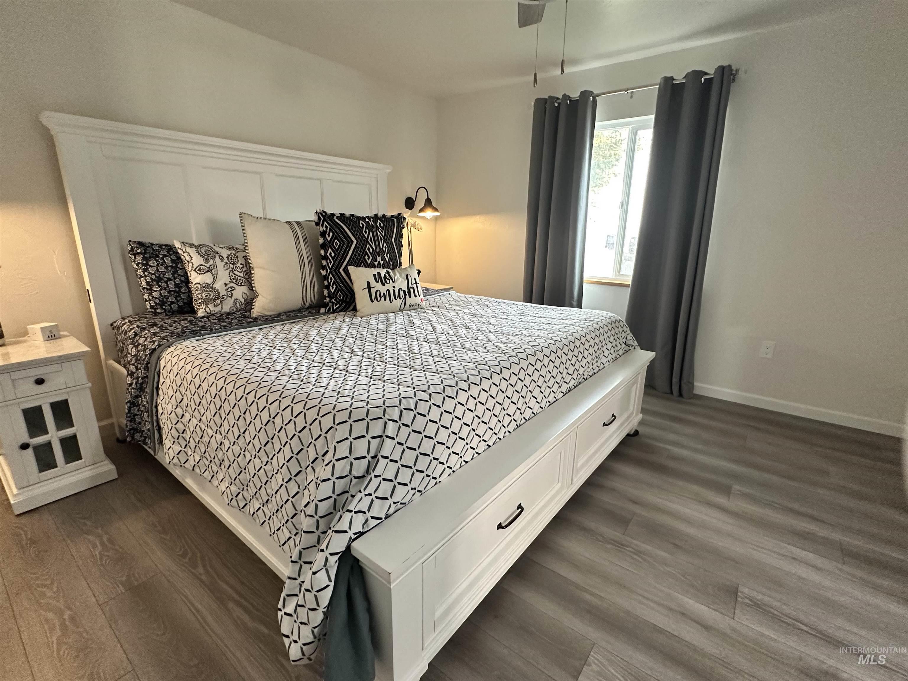Bedroom featuring dark wood-style floors and baseboards