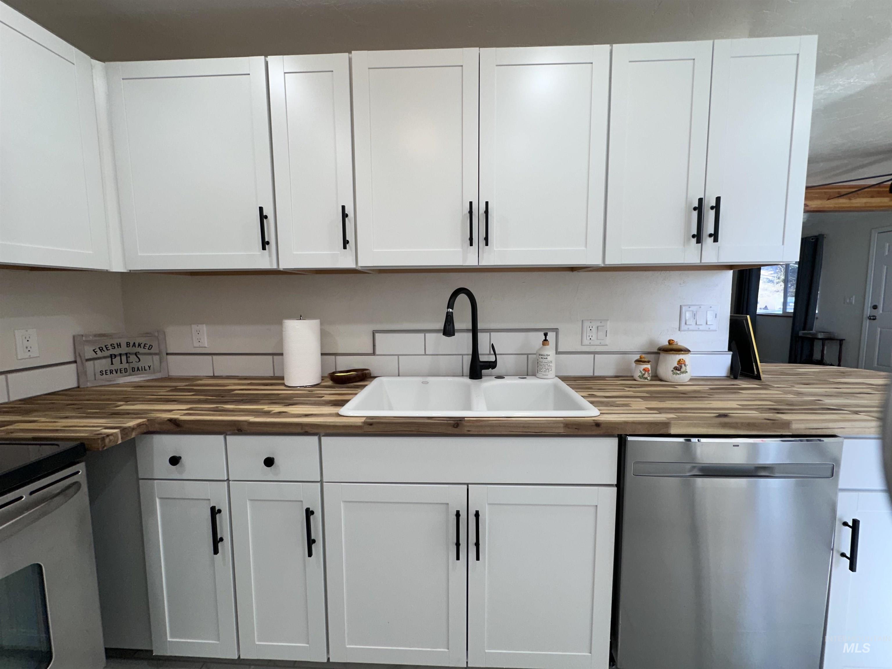Kitchen featuring butcher block counters, appliances with stainless steel finishes, and white cabinets