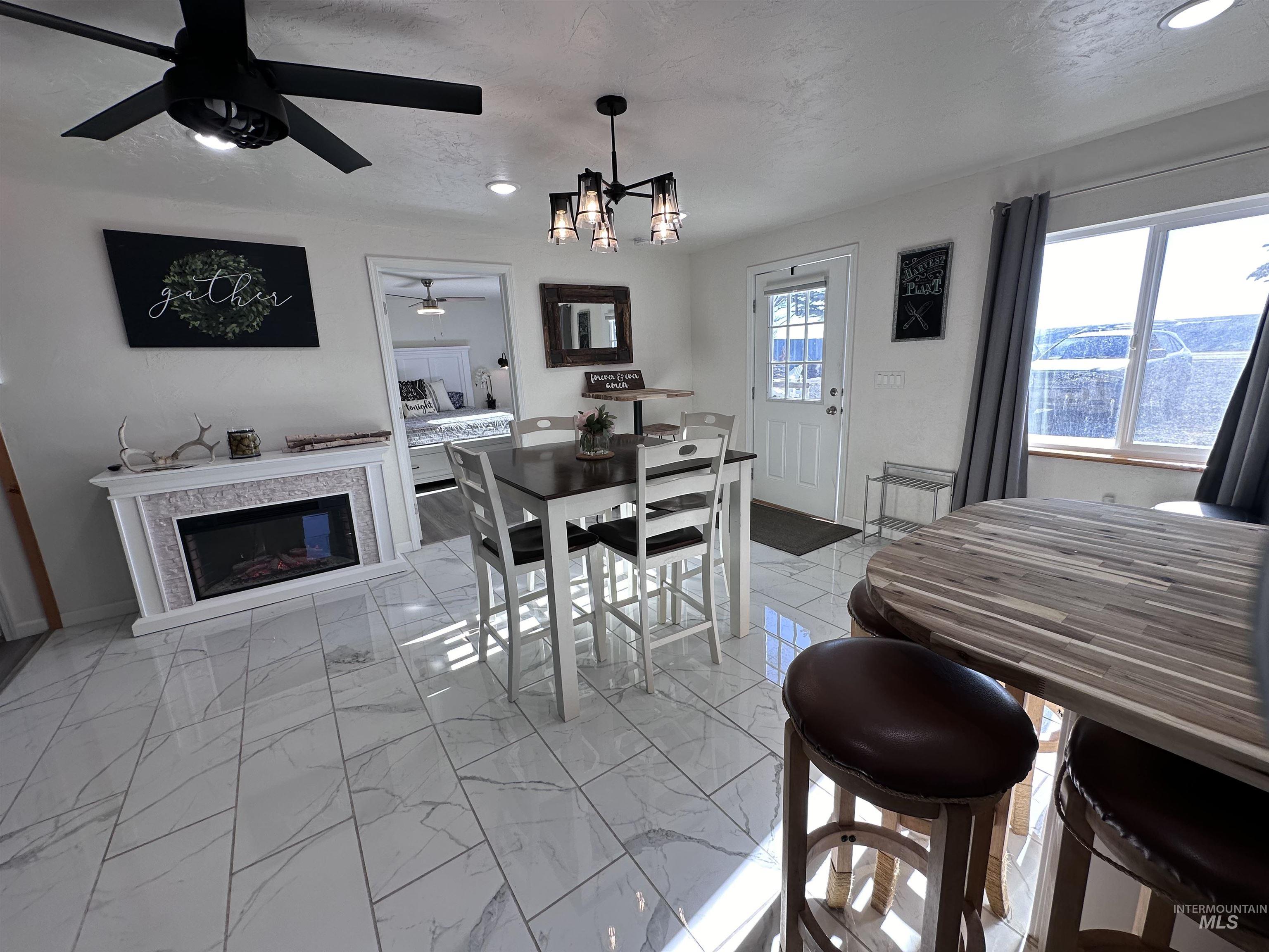 Dining space featuring a chandelier, light marble finish flooring, a glass covered fireplace, and a textured ceiling