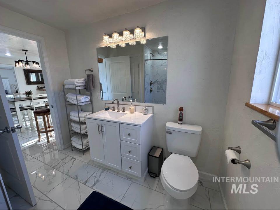 Full bath featuring vanity, light marble finish flooring, and a stall shower