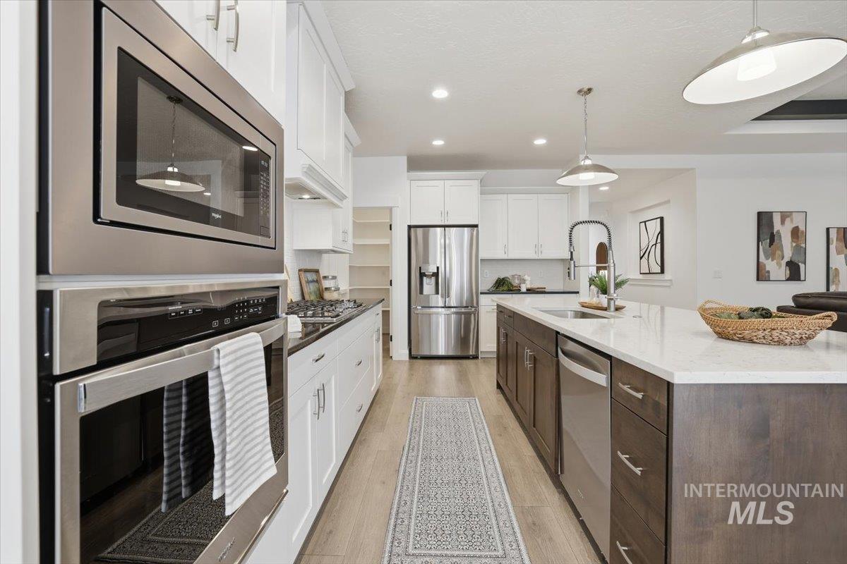 Kitchen with stainless steel appliances, recessed lighting, white cabinets, dark brown cabinetry, and pendant lighting