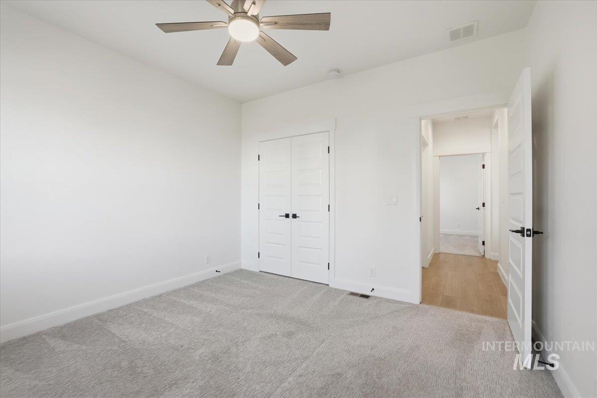 Unfurnished bedroom featuring light carpet, ceiling fan, and a closet