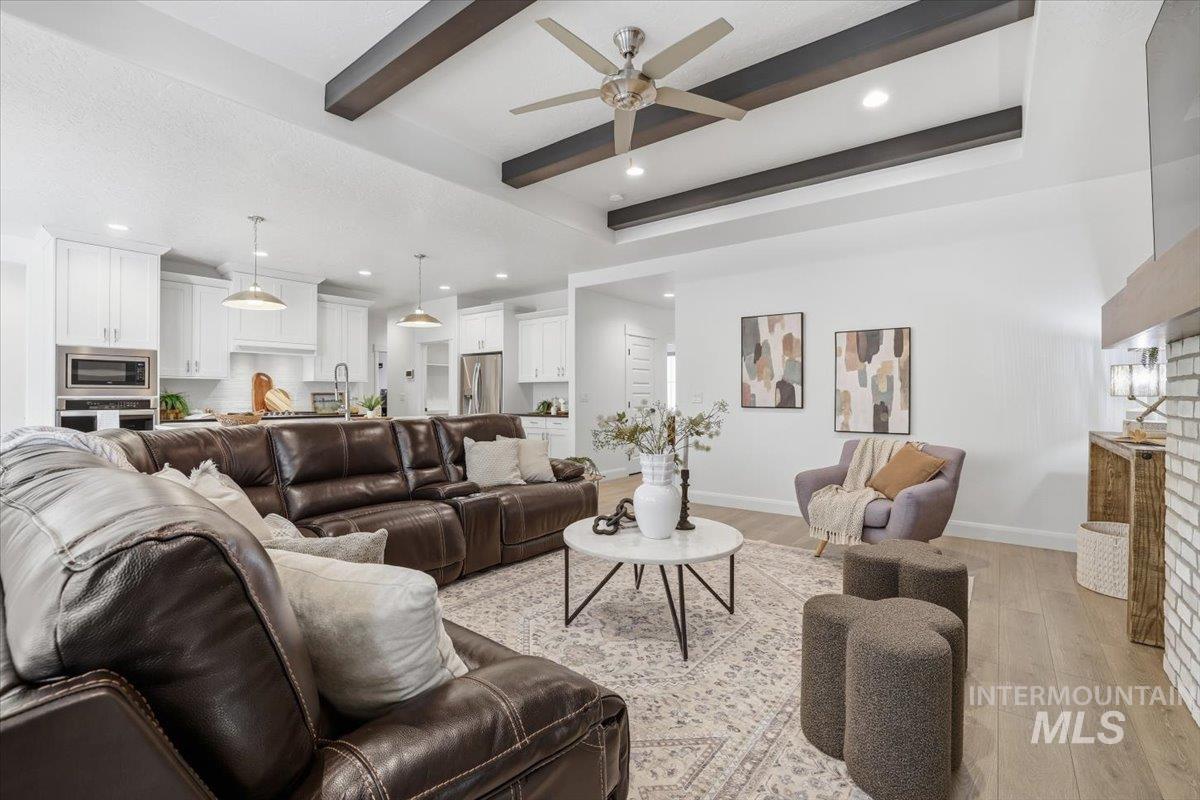 Living room featuring beam ceiling, light wood-style floors, recessed lighting, ceiling fan, and a fireplace