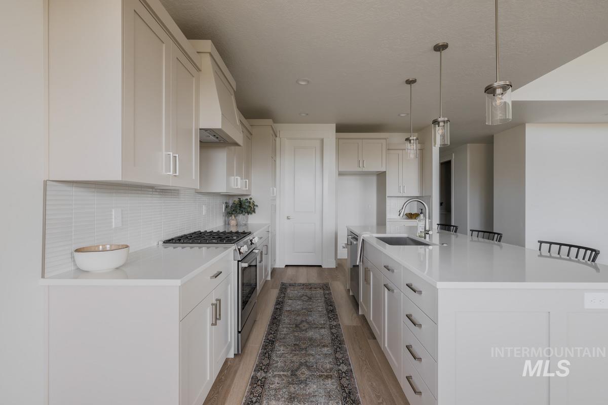 Kitchen featuring stainless steel appliances, light wood finished floors, tasteful backsplash, a kitchen bar, and recessed lighting