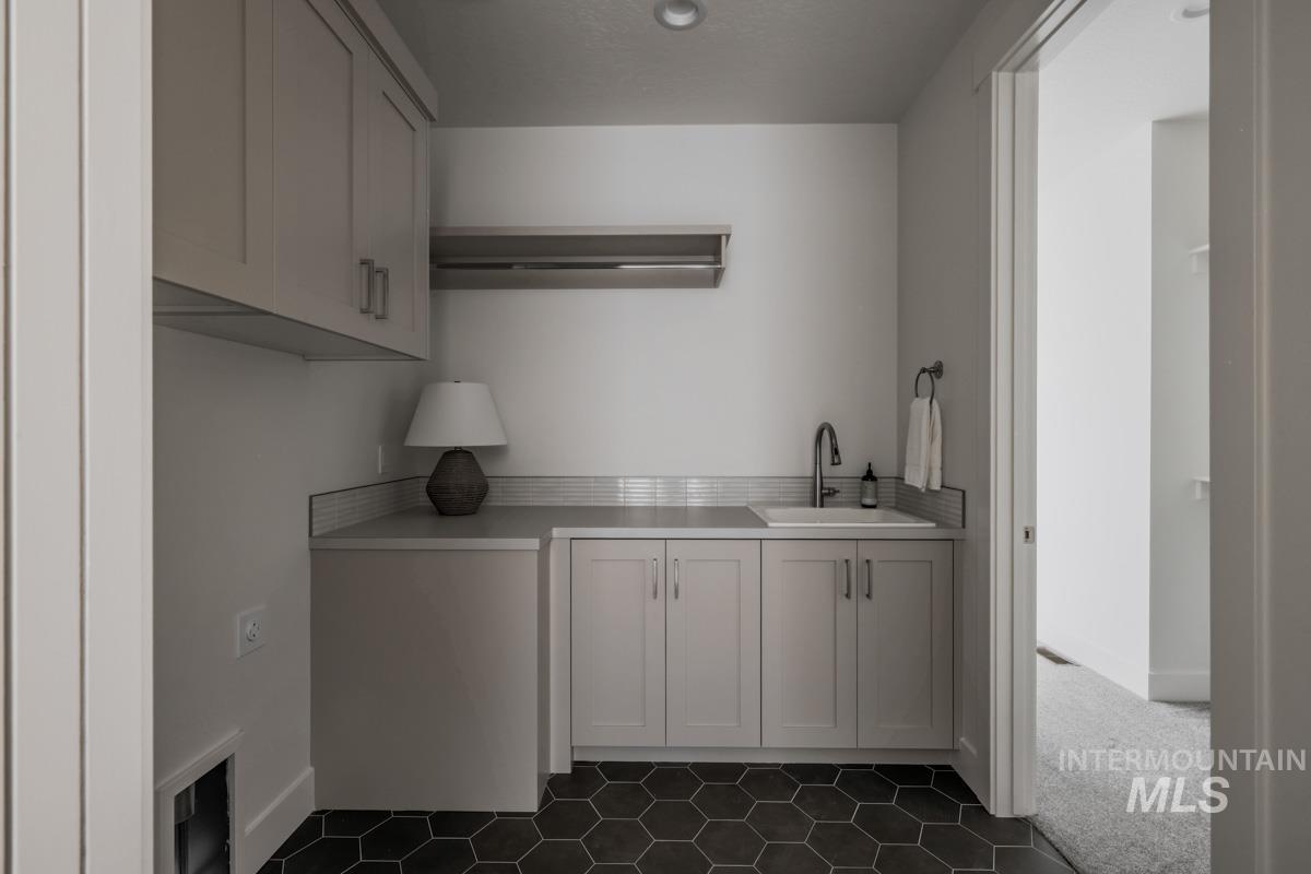 Laundry room with a sink and dark tile patterned floors