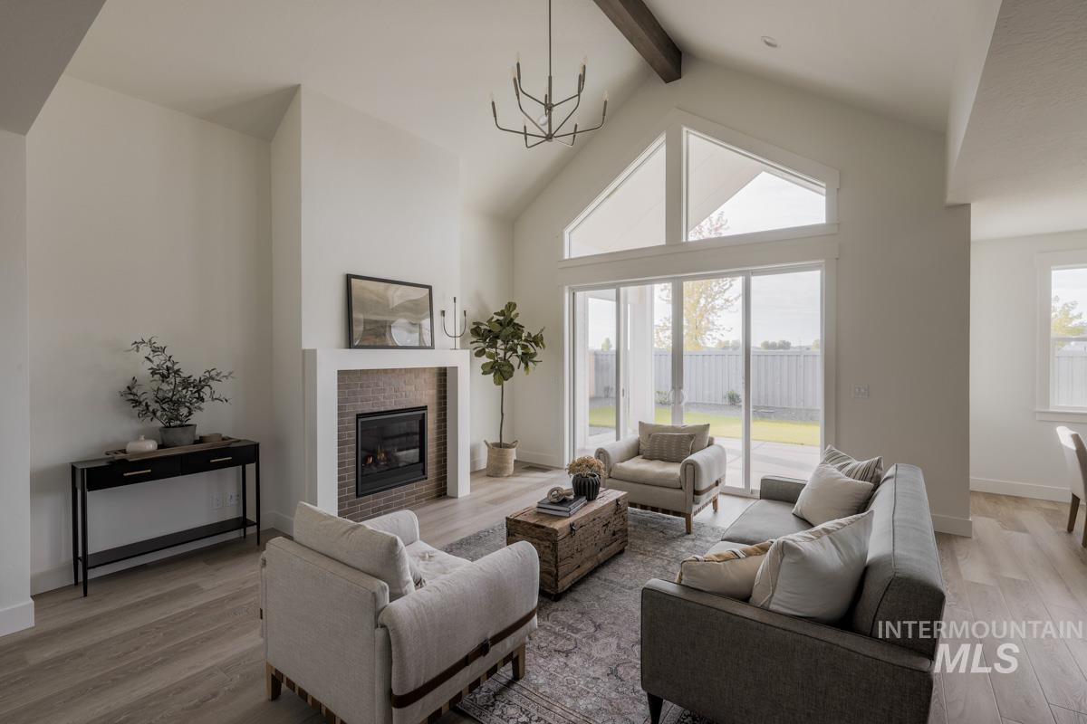 Living area with high vaulted ceiling, beamed ceiling, light wood-type flooring, a brick fireplace, and plenty of natural light