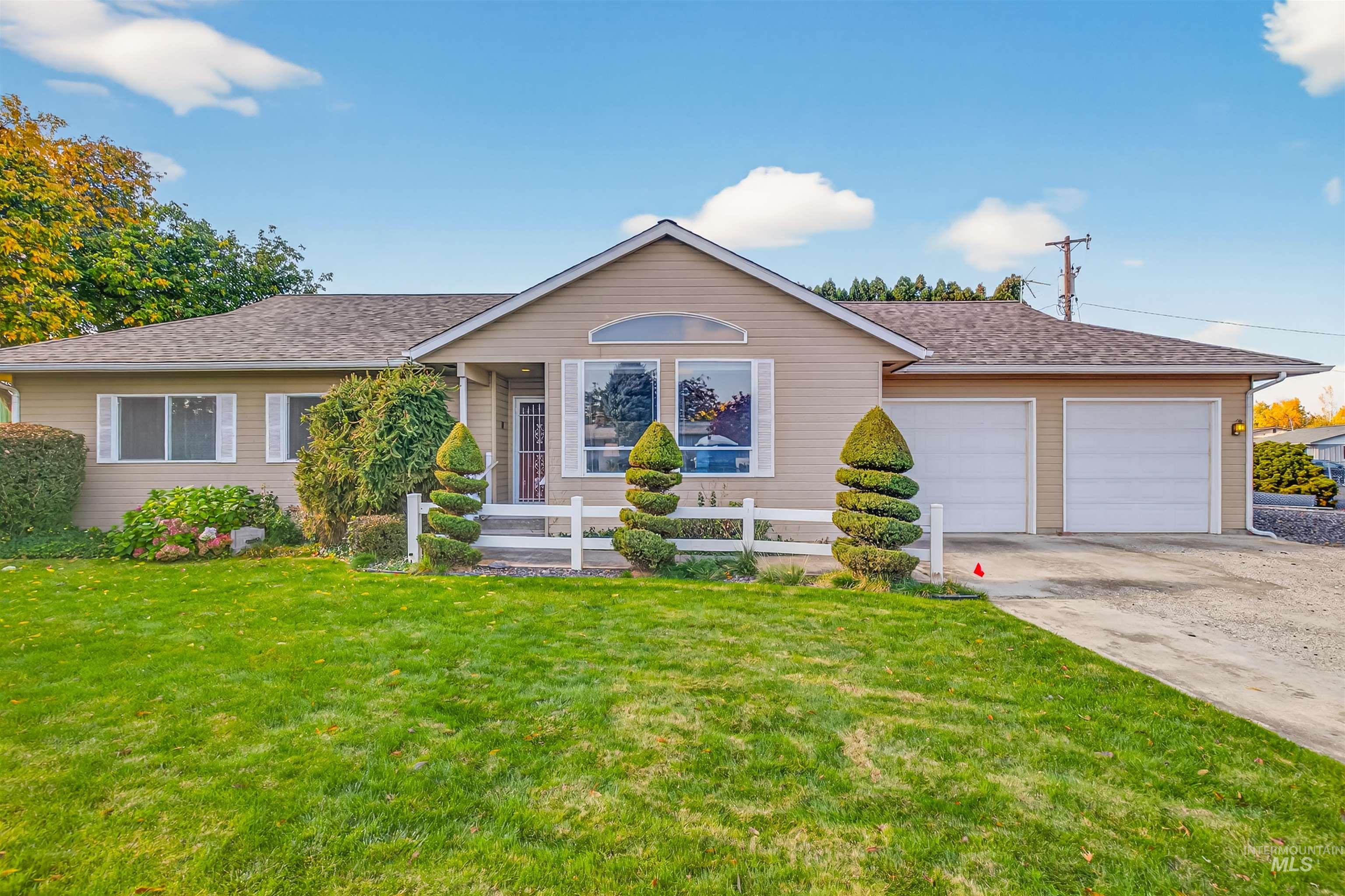 Ranch-style home featuring a front lawn, concrete driveway, roof with shingles, and an attached garage