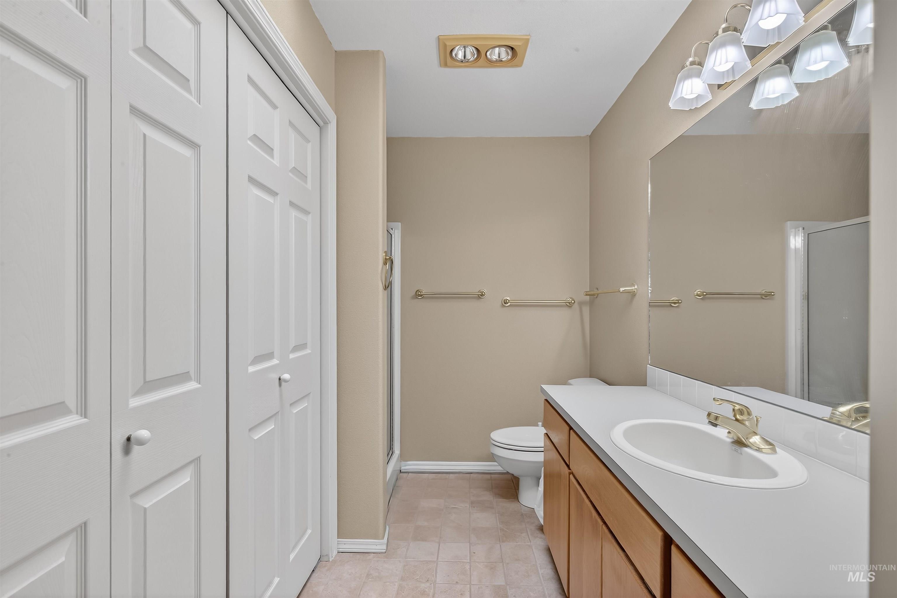 Bathroom featuring vanity, a closet, a shower stall, and light tile patterned floors