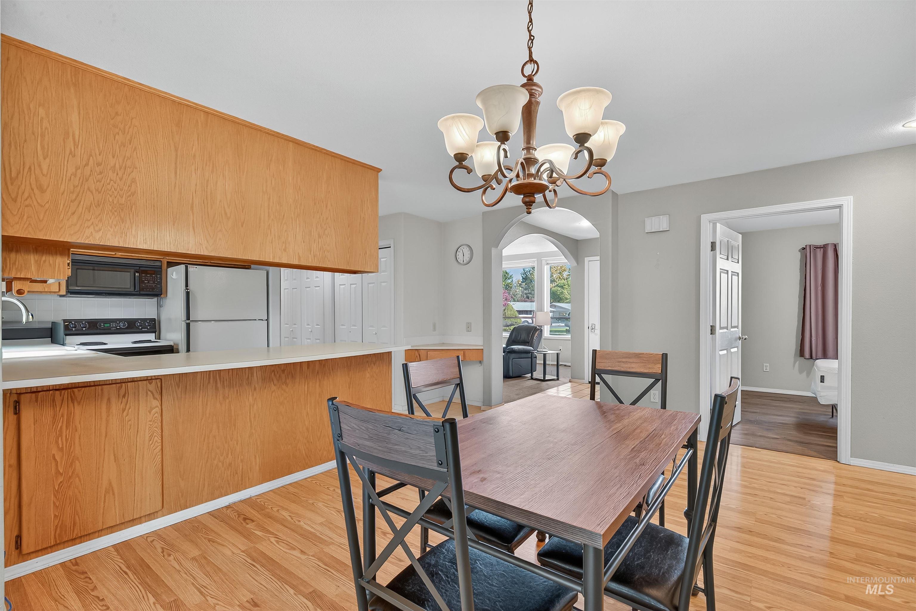 Dining space with light wood-style floors, a chandelier, and arched walkways