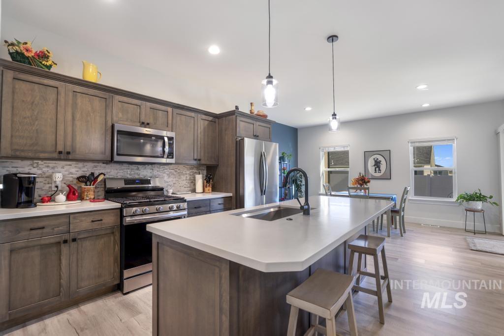 Kitchen with appliances with stainless steel finishes, tasteful backsplash, dark brown cabinetry, light countertops, and recessed lighting
