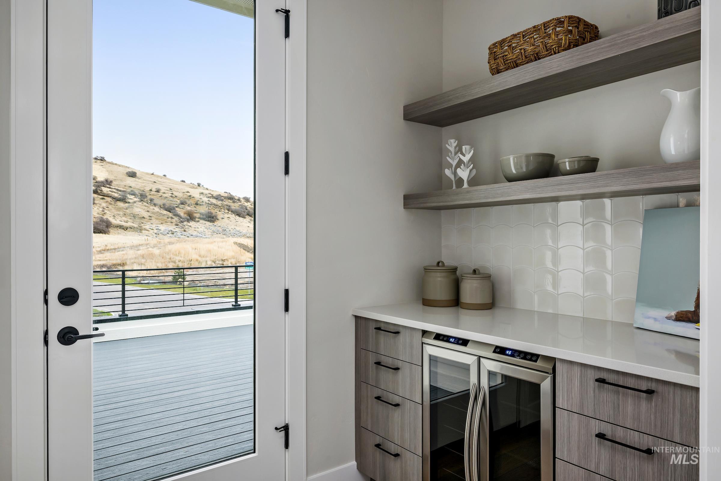 Bar with beverage cooler, modern cabinets, tasteful backsplash, open shelves, and light stone countertops