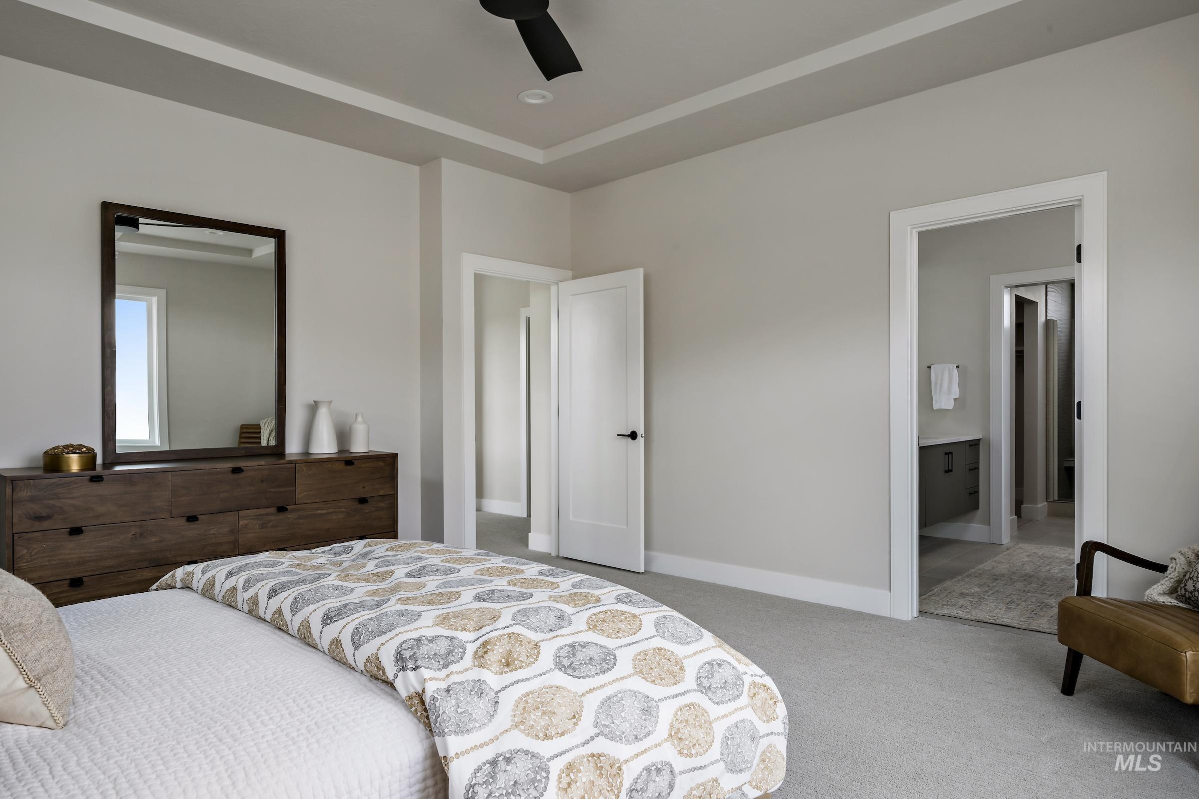 Carpeted bedroom with ceiling fan and ensuite bath