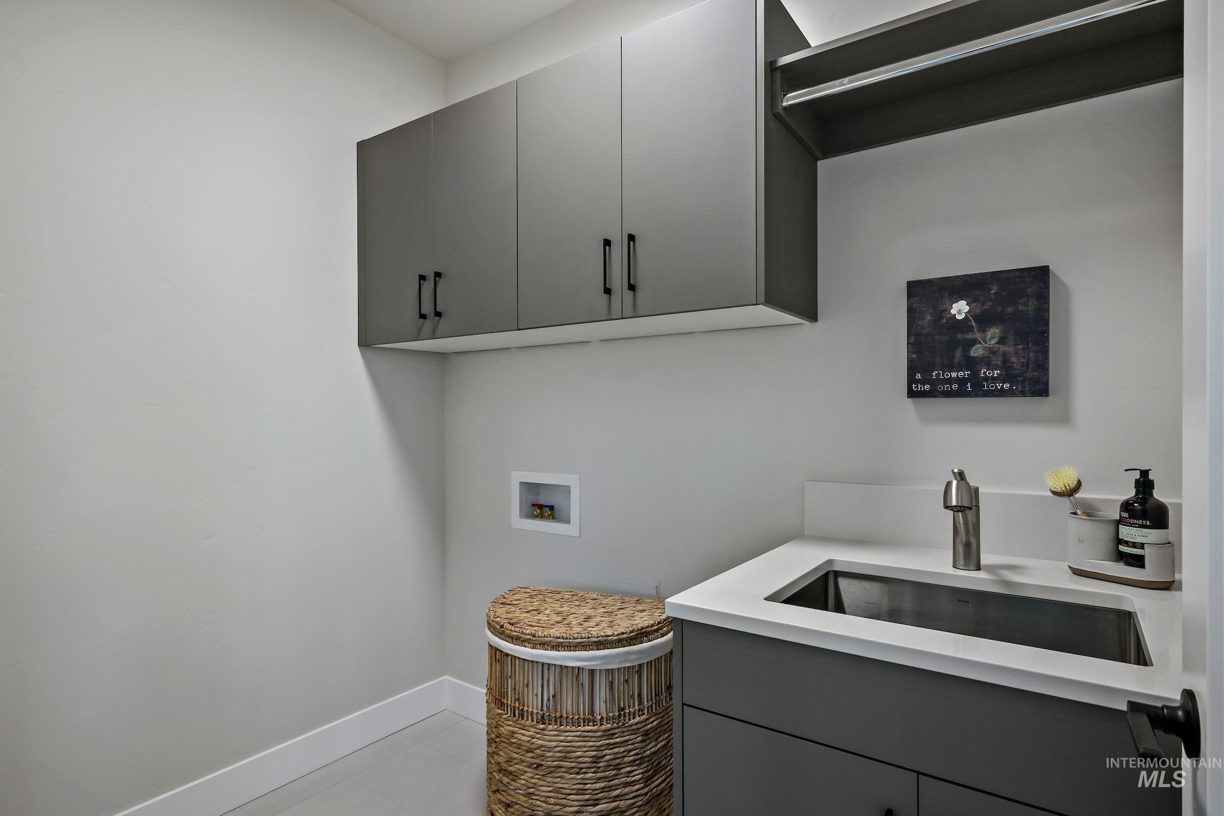 Washroom with hookup for a washing machine, cabinet space, and light tile patterned floors