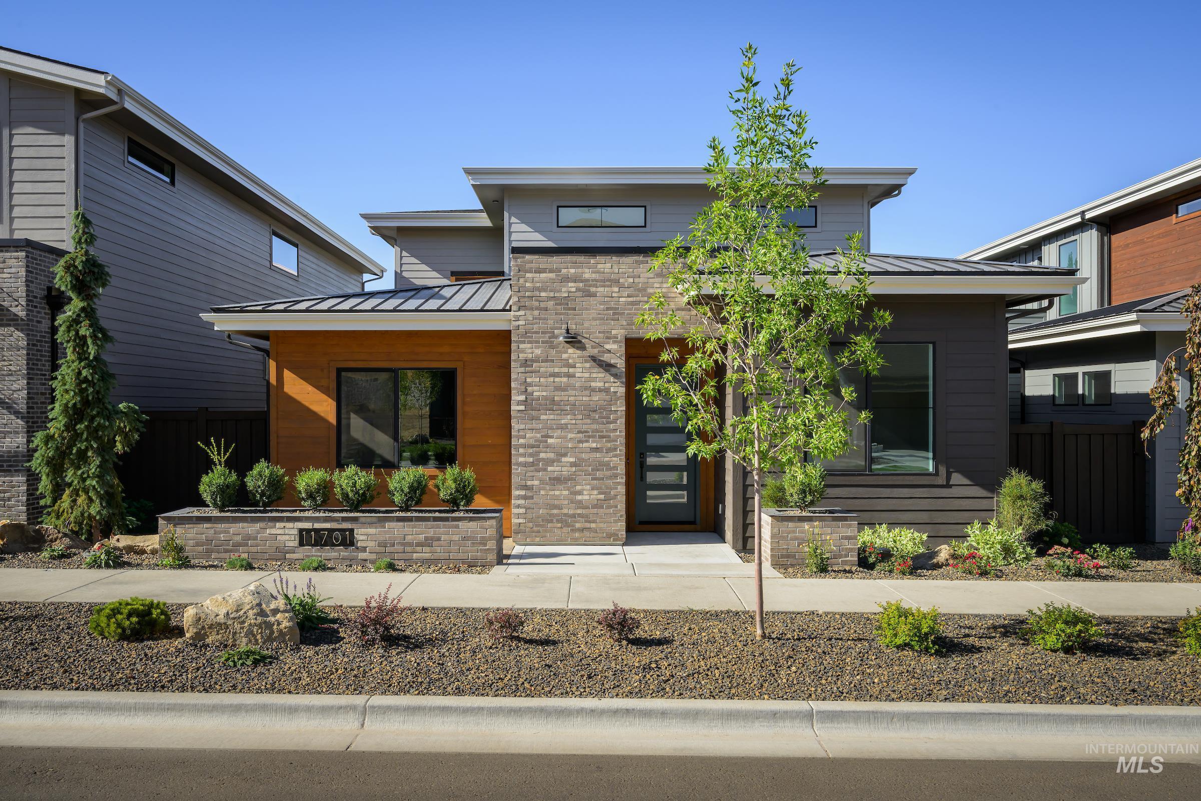 Contemporary house featuring a standing seam roof, a metal roof, and brick siding