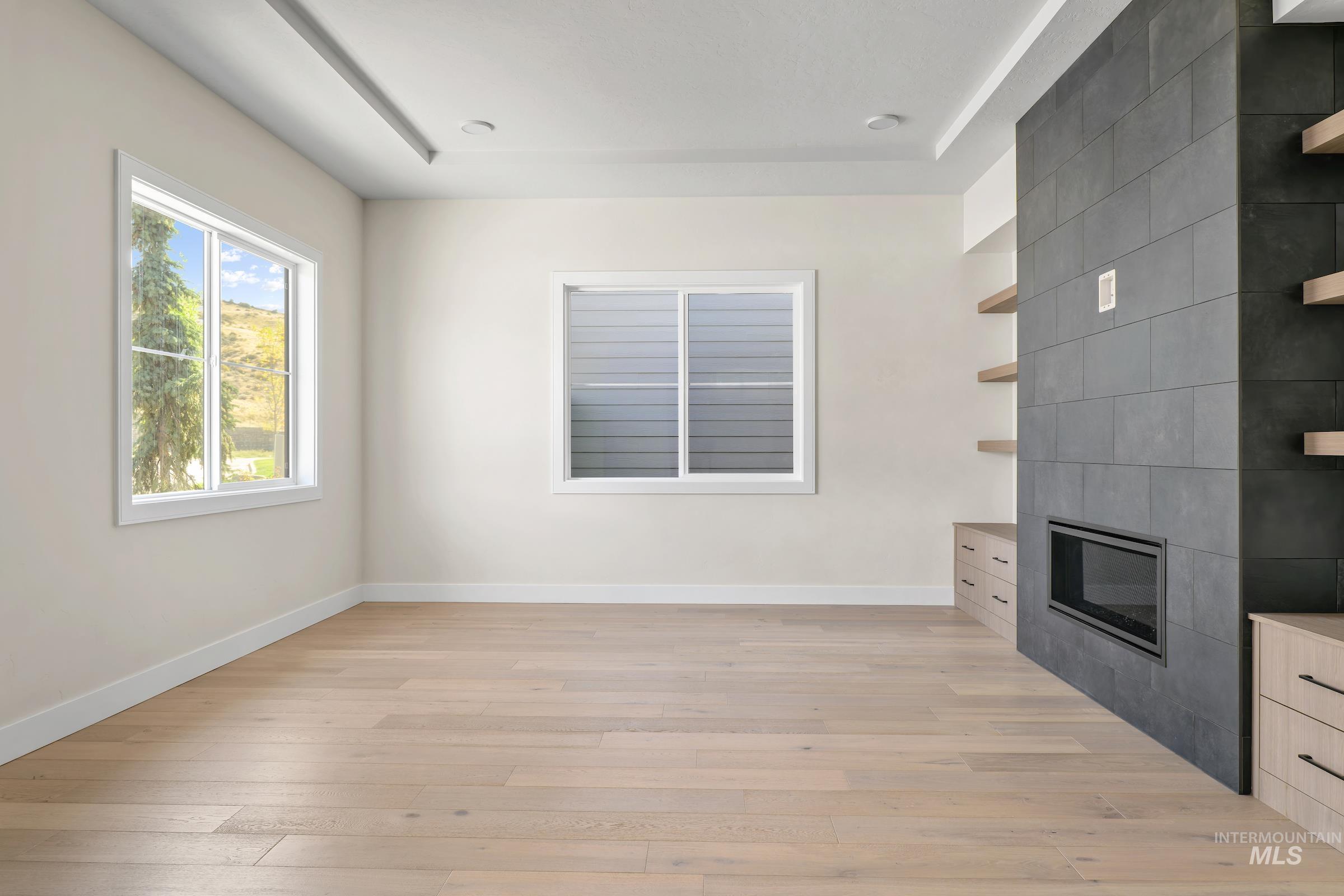 Unfurnished living room featuring light wood finished floors and a tiled fireplace