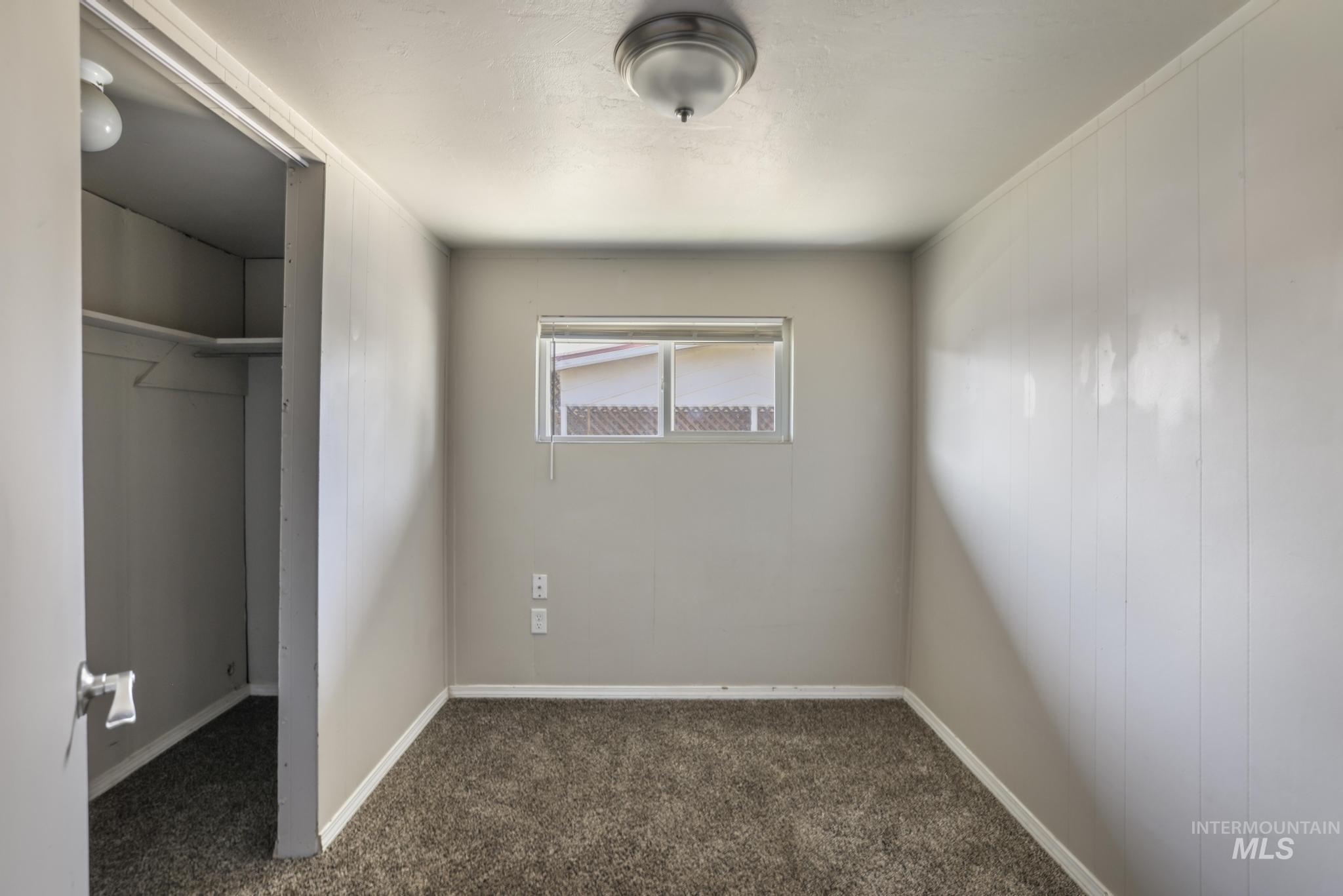 Unfurnished bedroom featuring dark colored carpet and baseboards