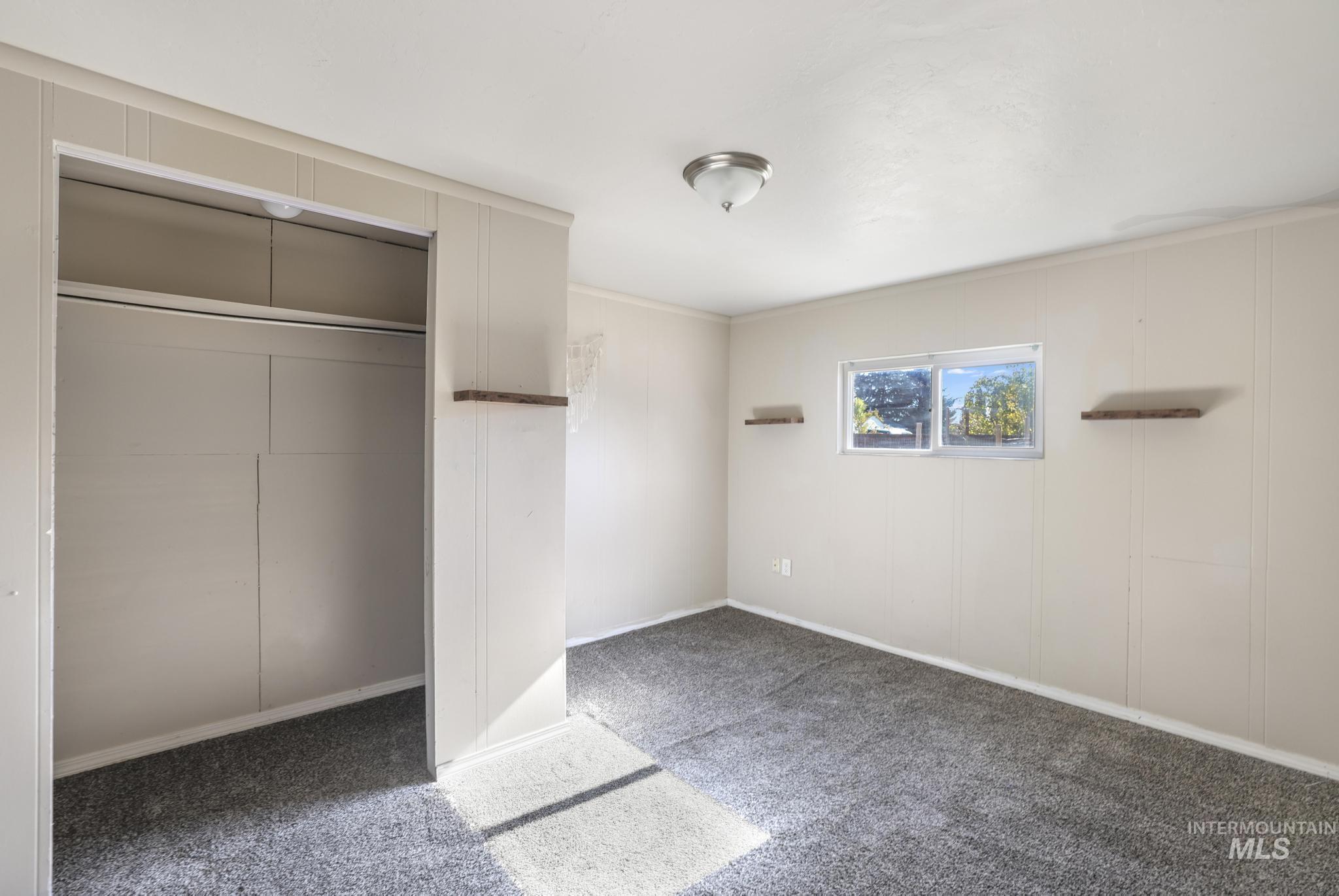 Unfurnished bedroom with dark carpet, a closet, and ornamental molding