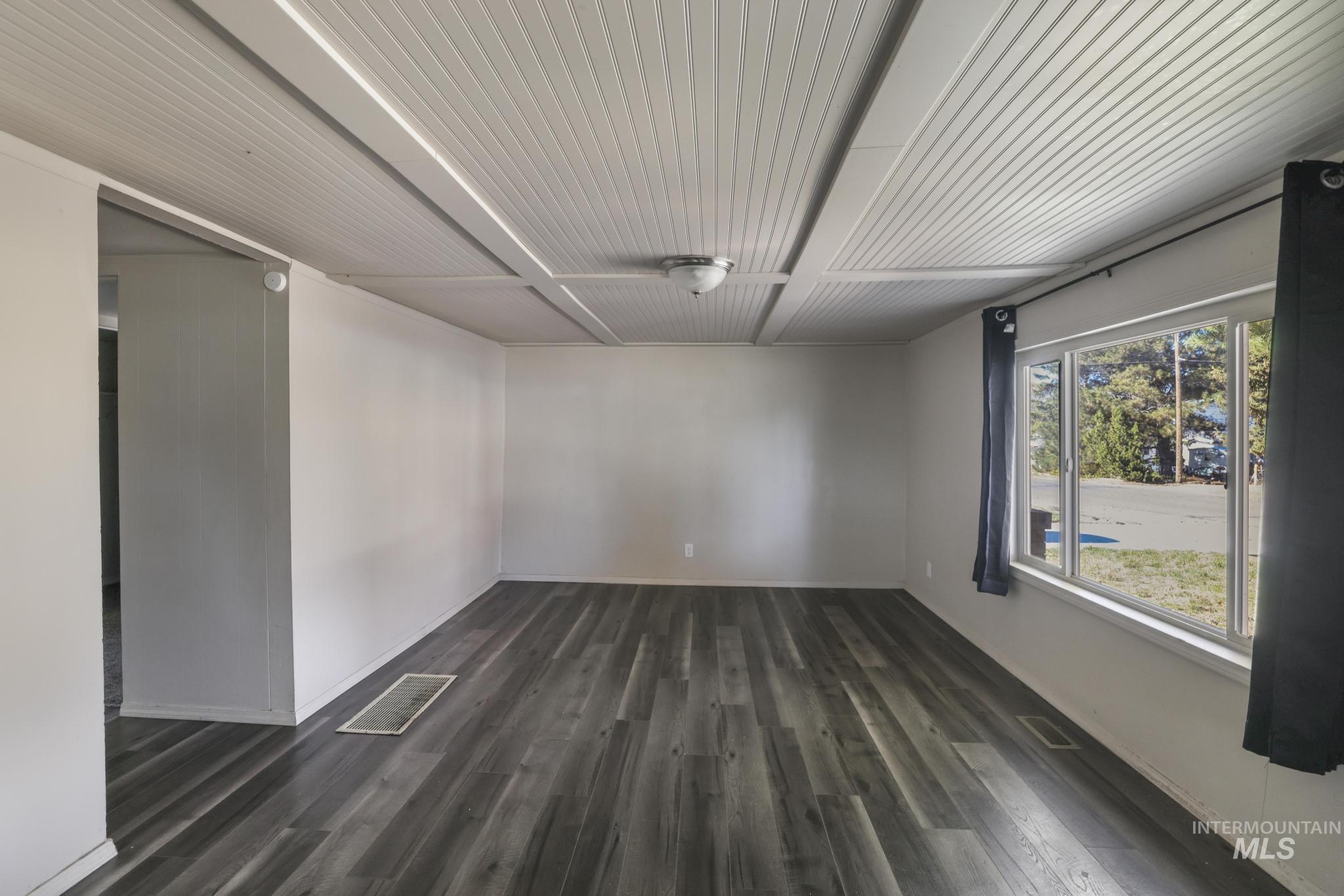 Spare room featuring dark wood-style floors and baseboards