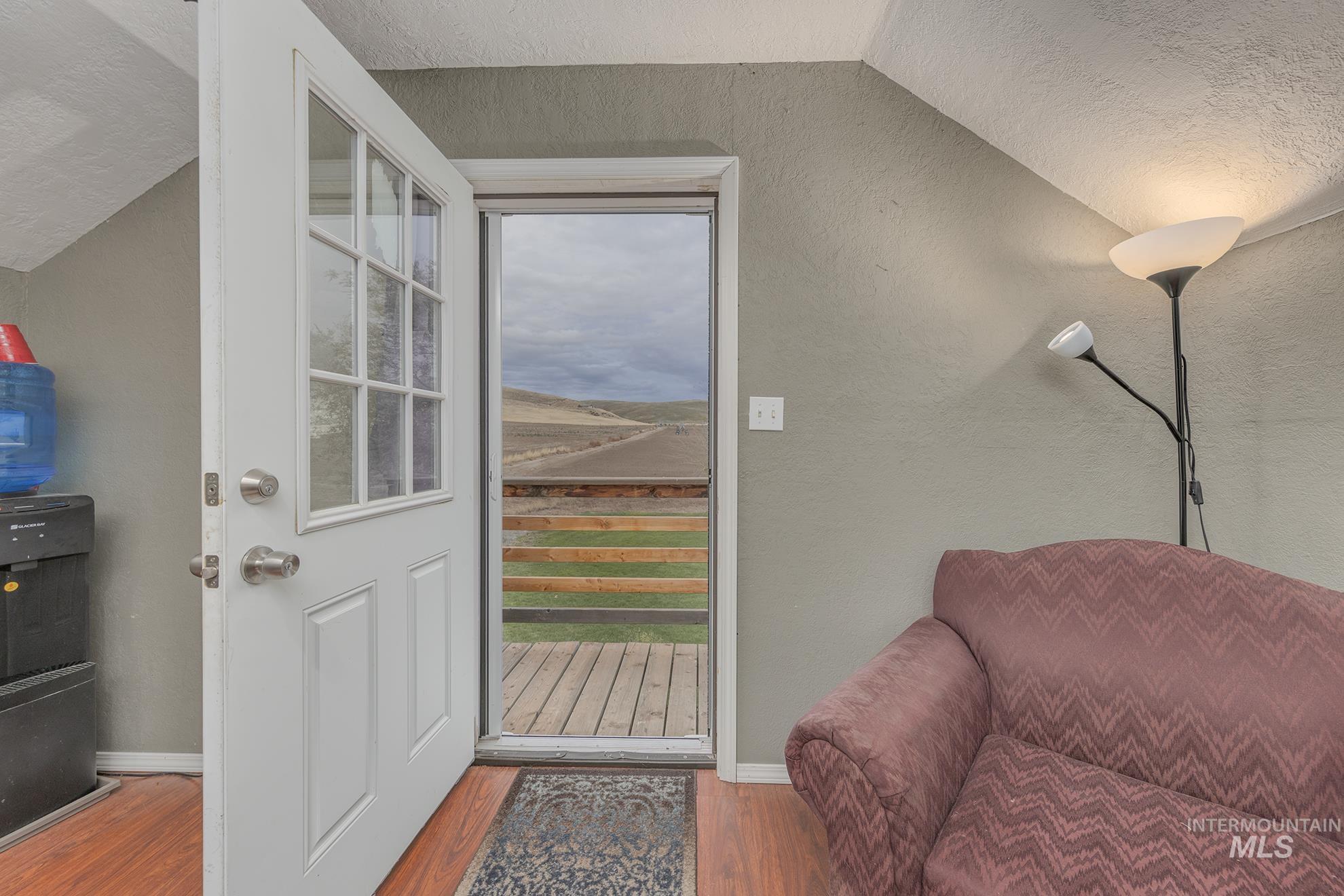 Entryway with wood finished floors, plenty of natural light, a textured ceiling, a textured wall, and lofted ceiling