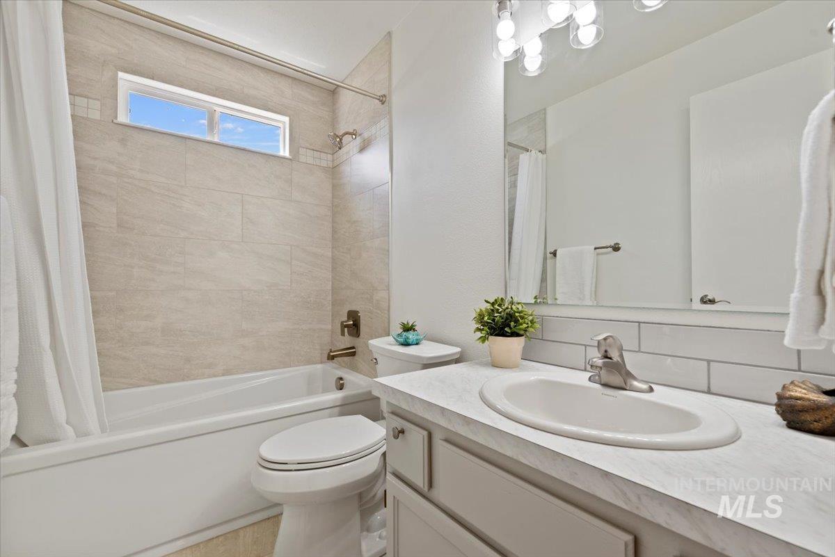 Full bathroom featuring vanity, shower / bath combo, and backsplash