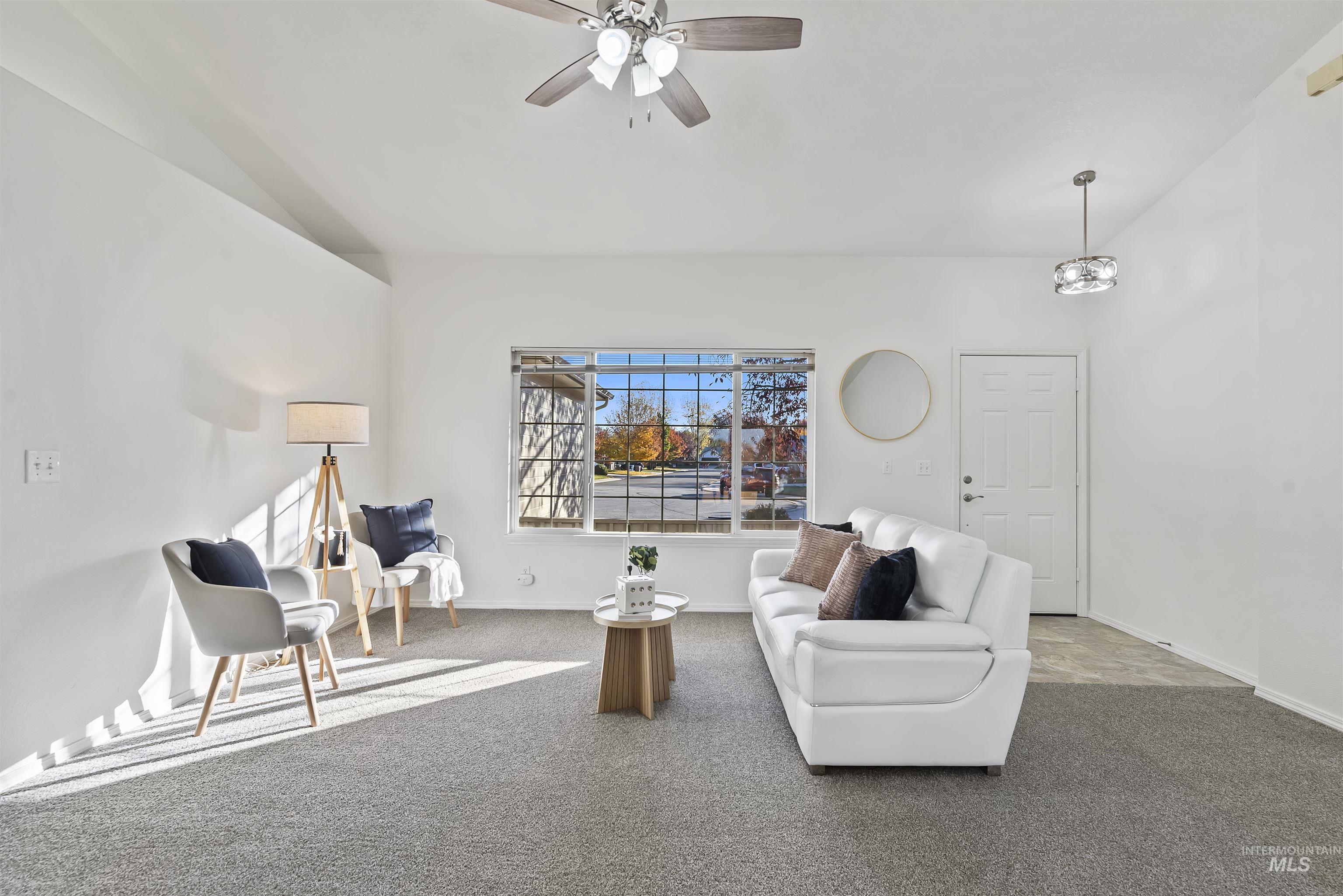 Living area featuring carpet flooring, ceiling fan, and vaulted ceiling
