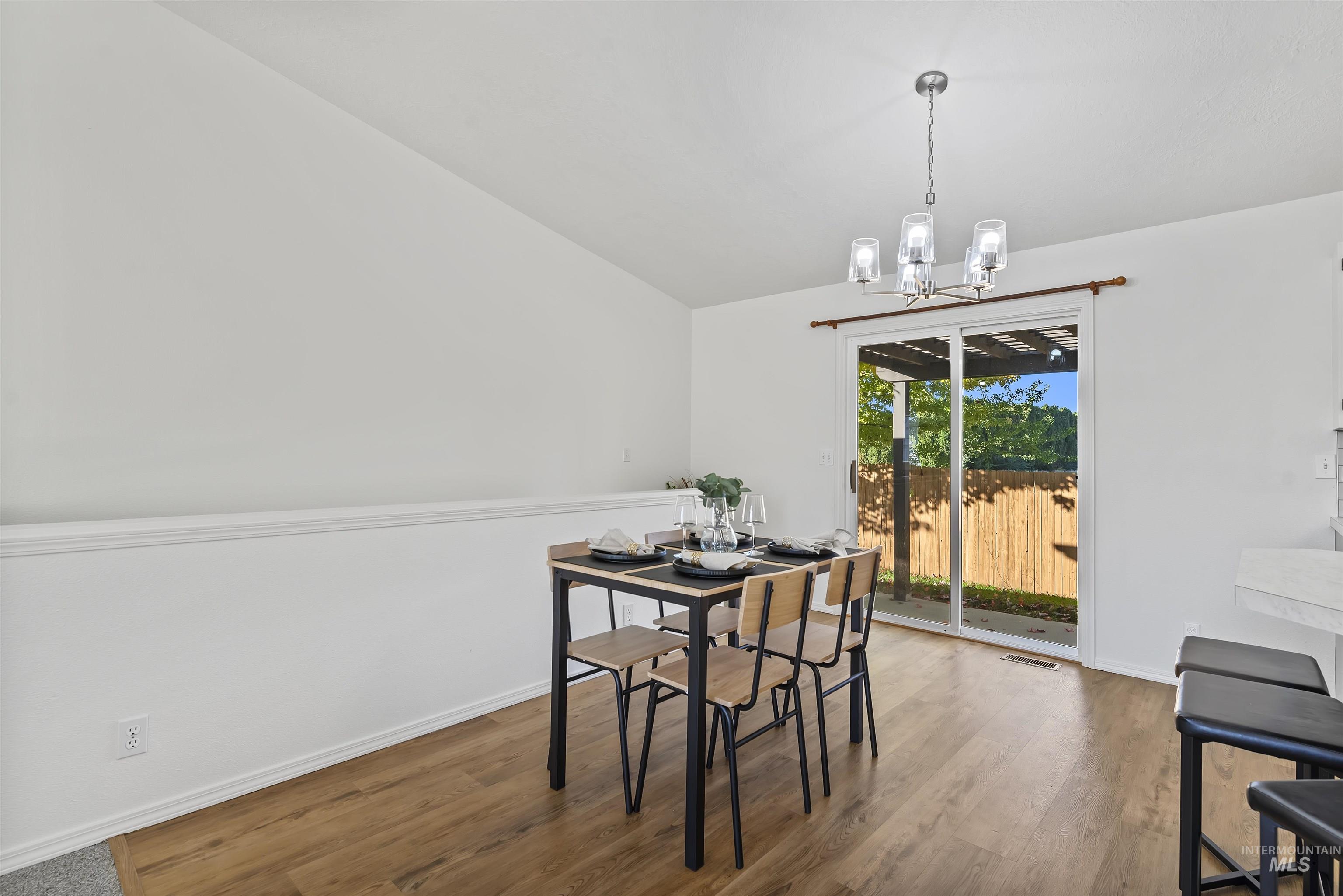 Dining room featuring wood finished floors, a chandelier, and vaulted ceiling