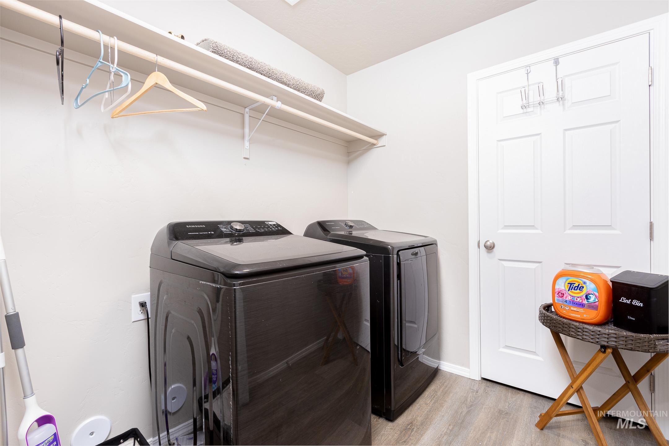 Laundry area with light wood finished floors and washing machine and clothes dryer