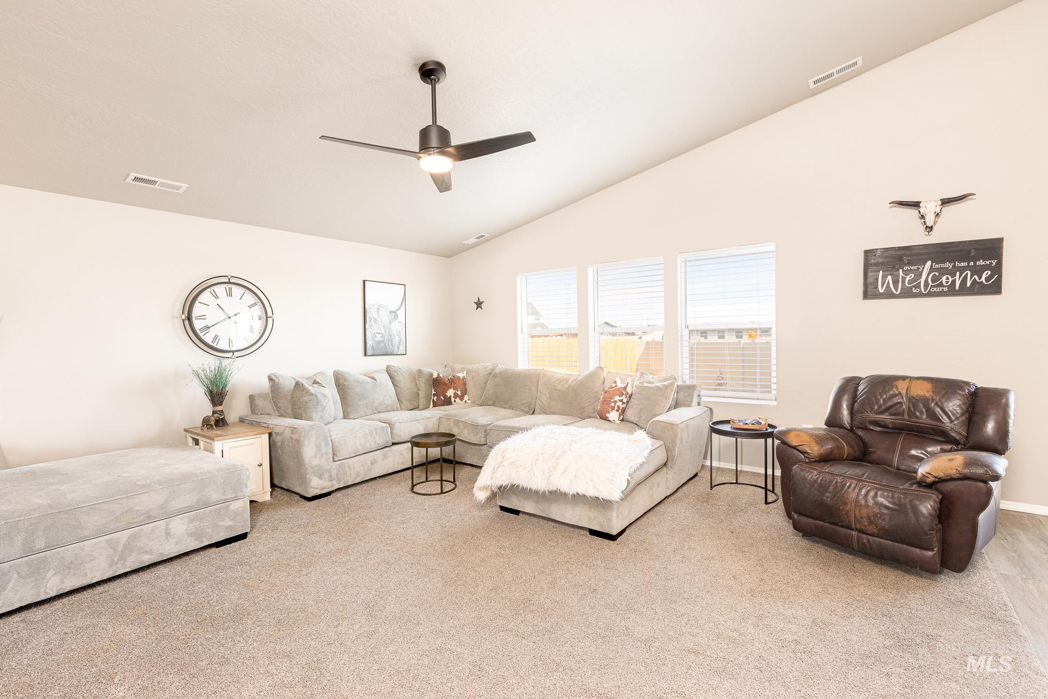 Living room featuring lofted ceiling, light carpet, and ceiling fan