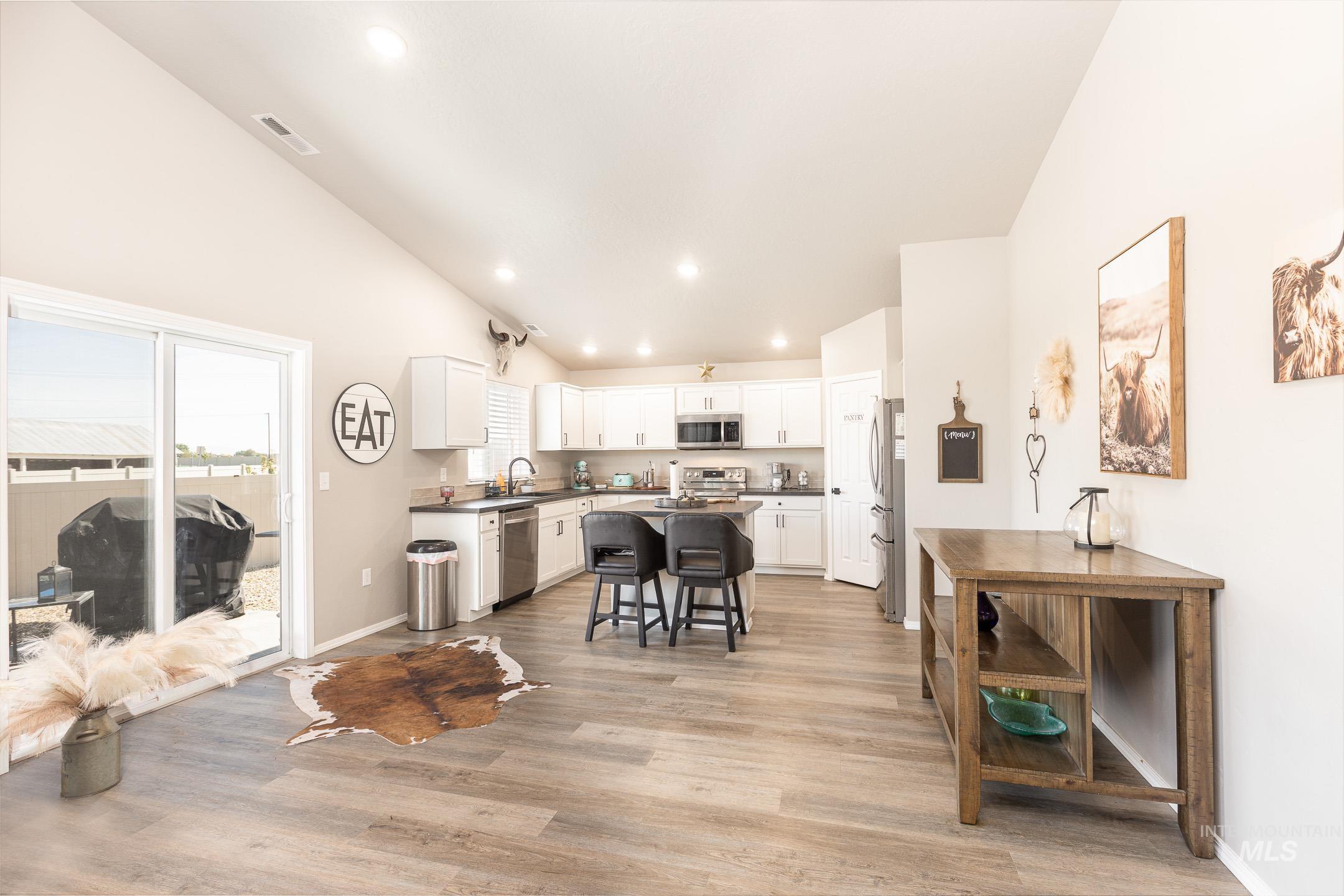 Kitchen featuring recessed lighting, dark countertops, white cabinets, a kitchen bar, and light wood-style floors