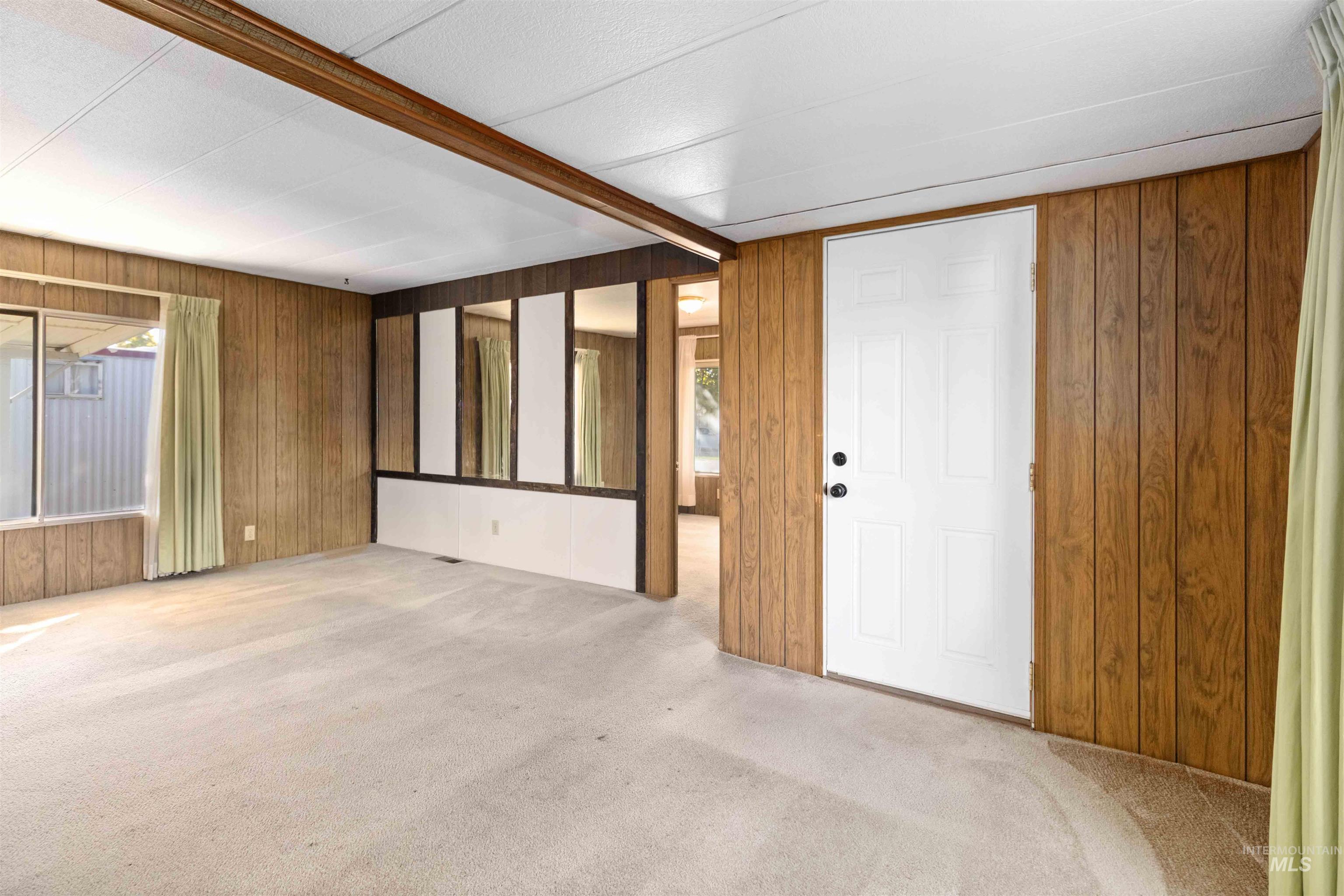 Foyer entrance featuring wooden walls, beamed ceiling, carpet floors, and plenty of natural light