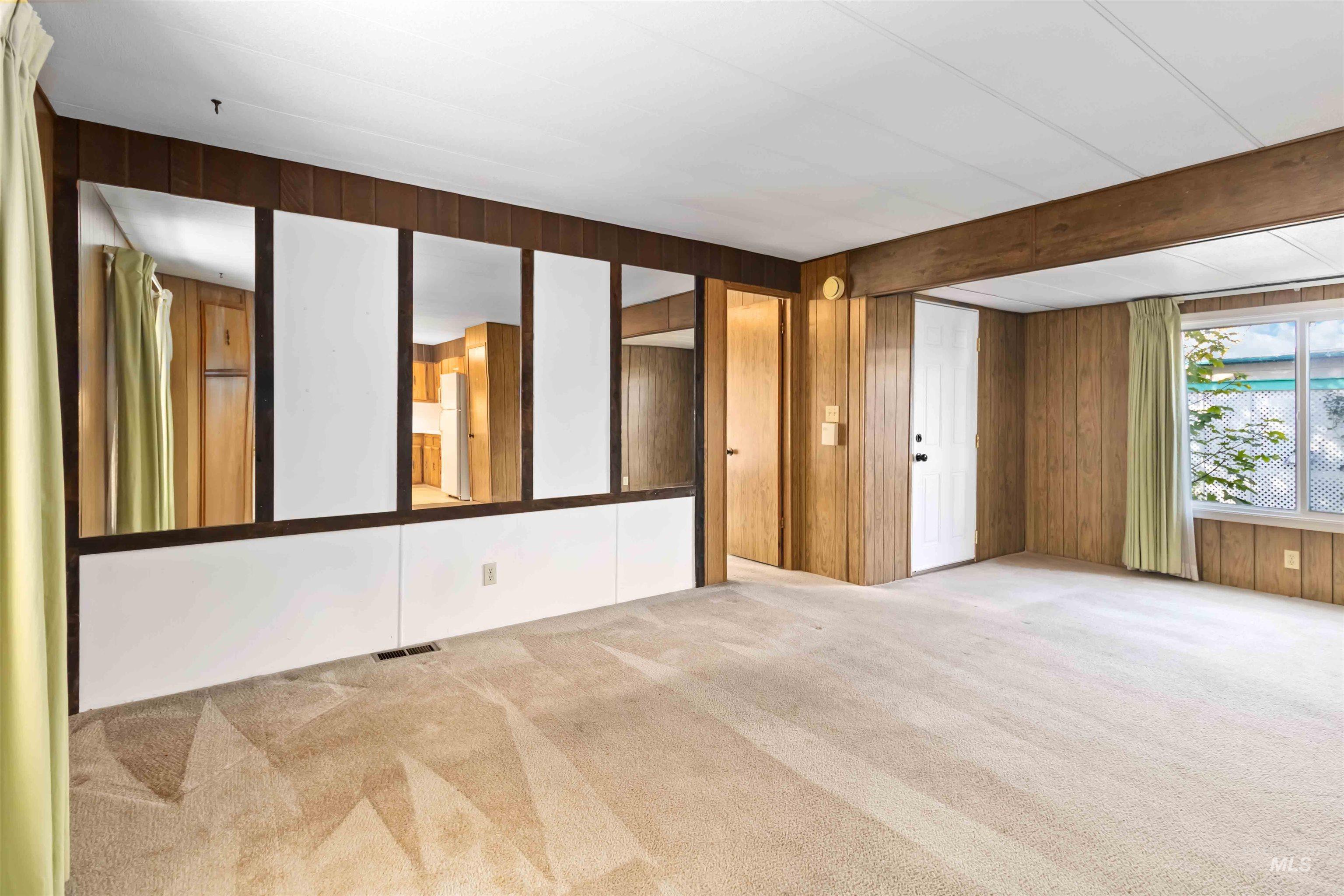 Carpeted empty room with wood walls and beamed ceiling