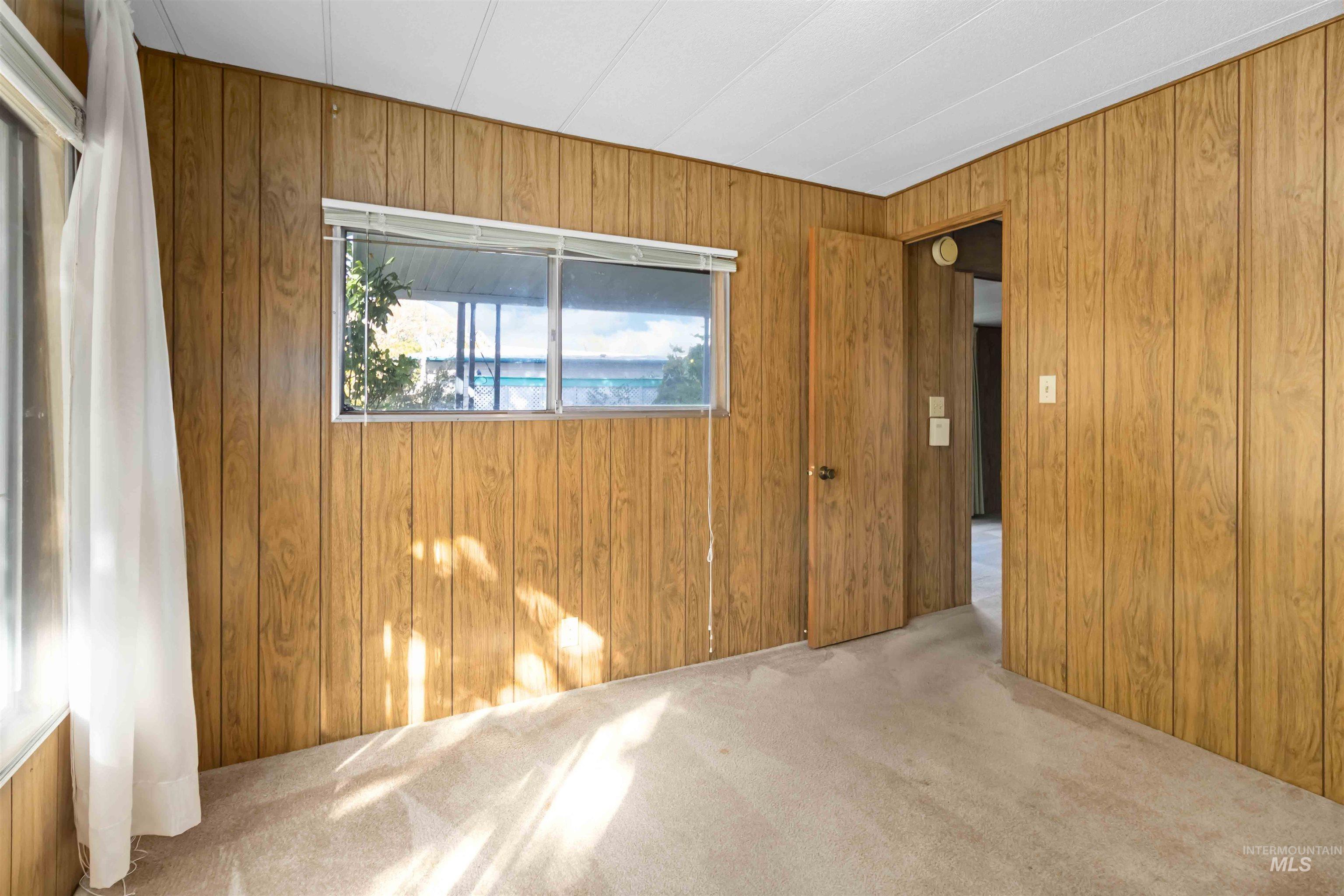 Empty room featuring wood walls and light carpet