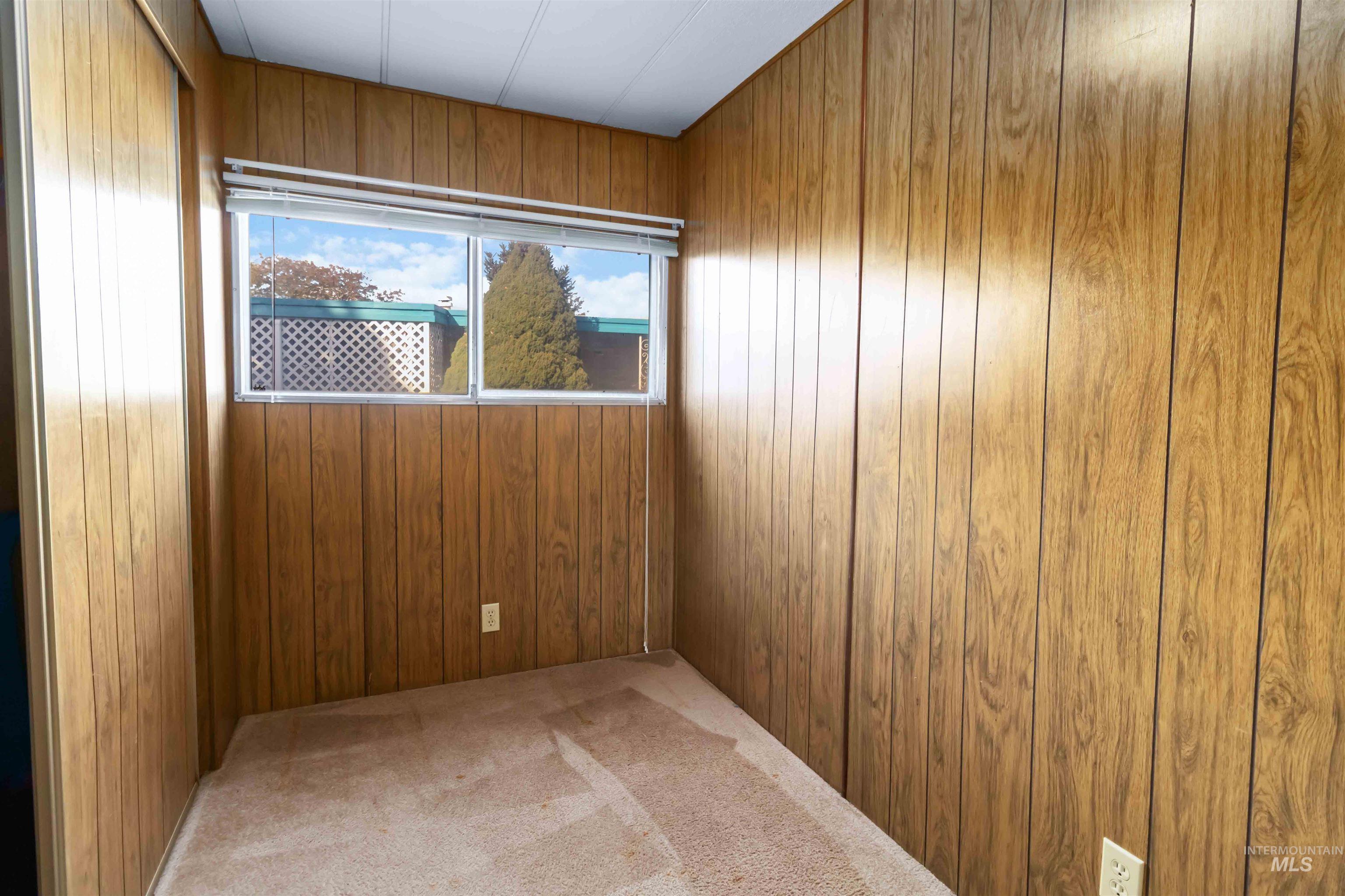 Spare room featuring light colored carpet and wooden walls