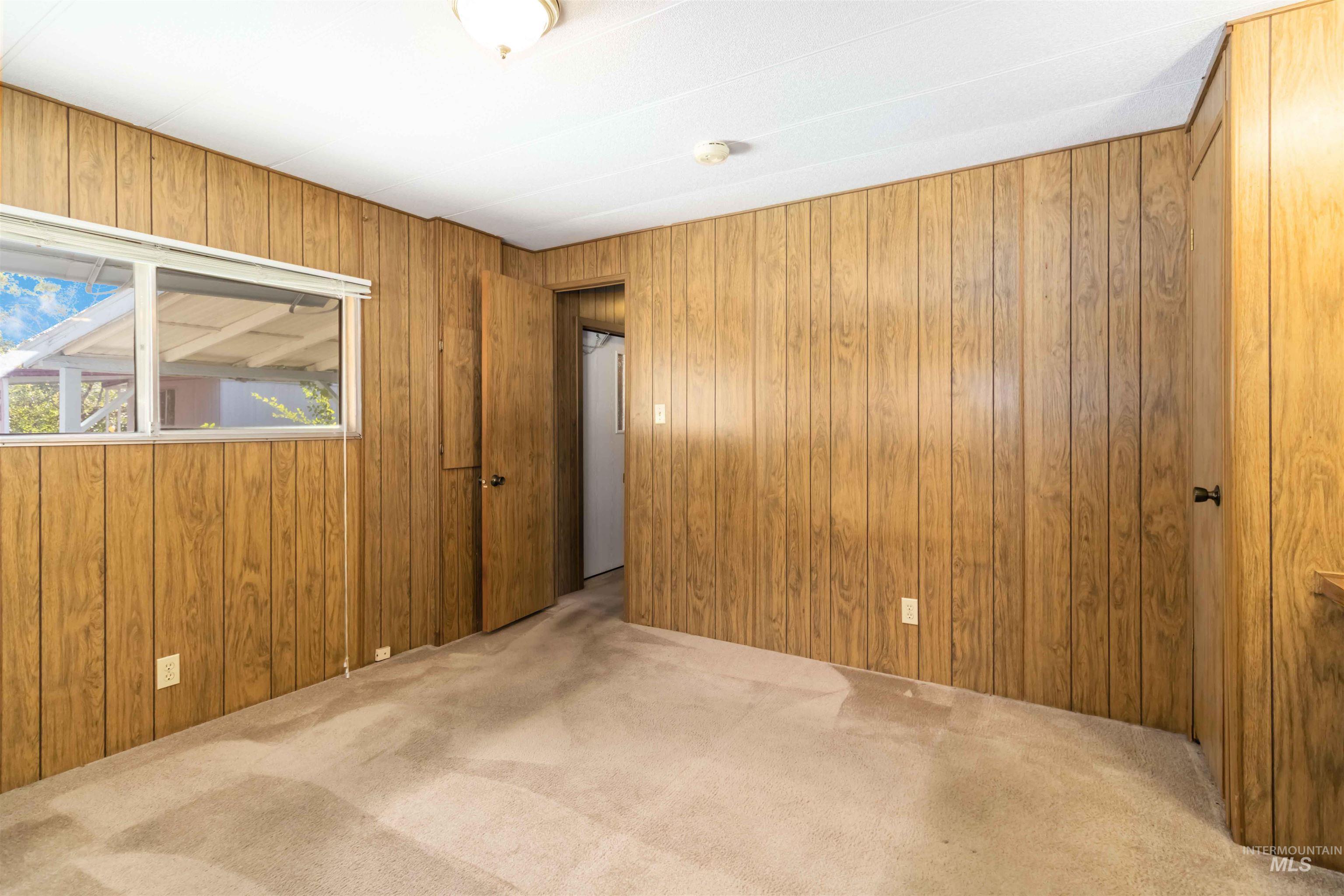 Unfurnished room with carpet flooring and wood walls