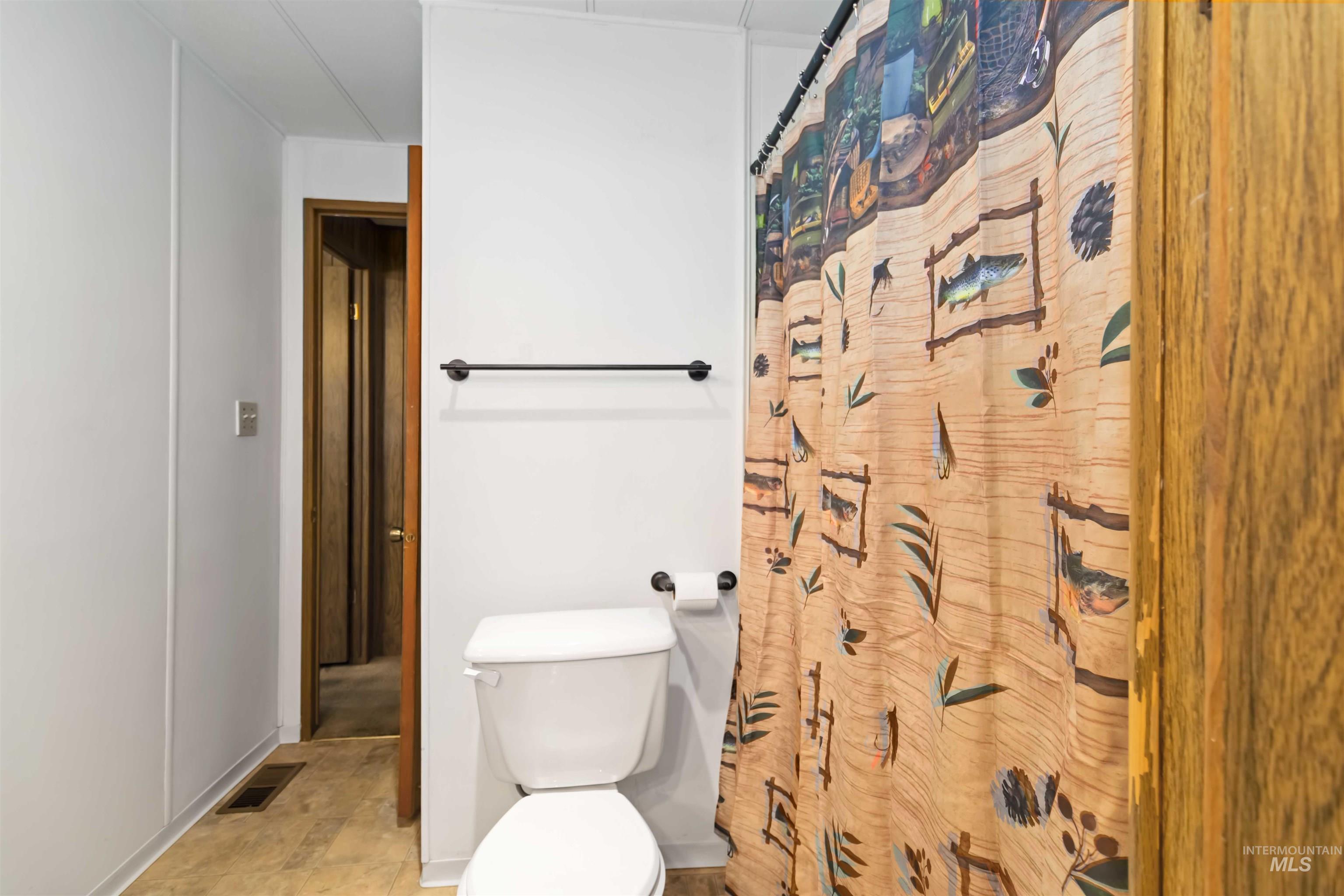 Full bath with a shower with shower curtain and toilet