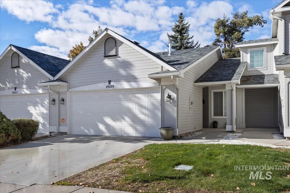 View of front of home with concrete driveway, a front lawn, and an attached garage