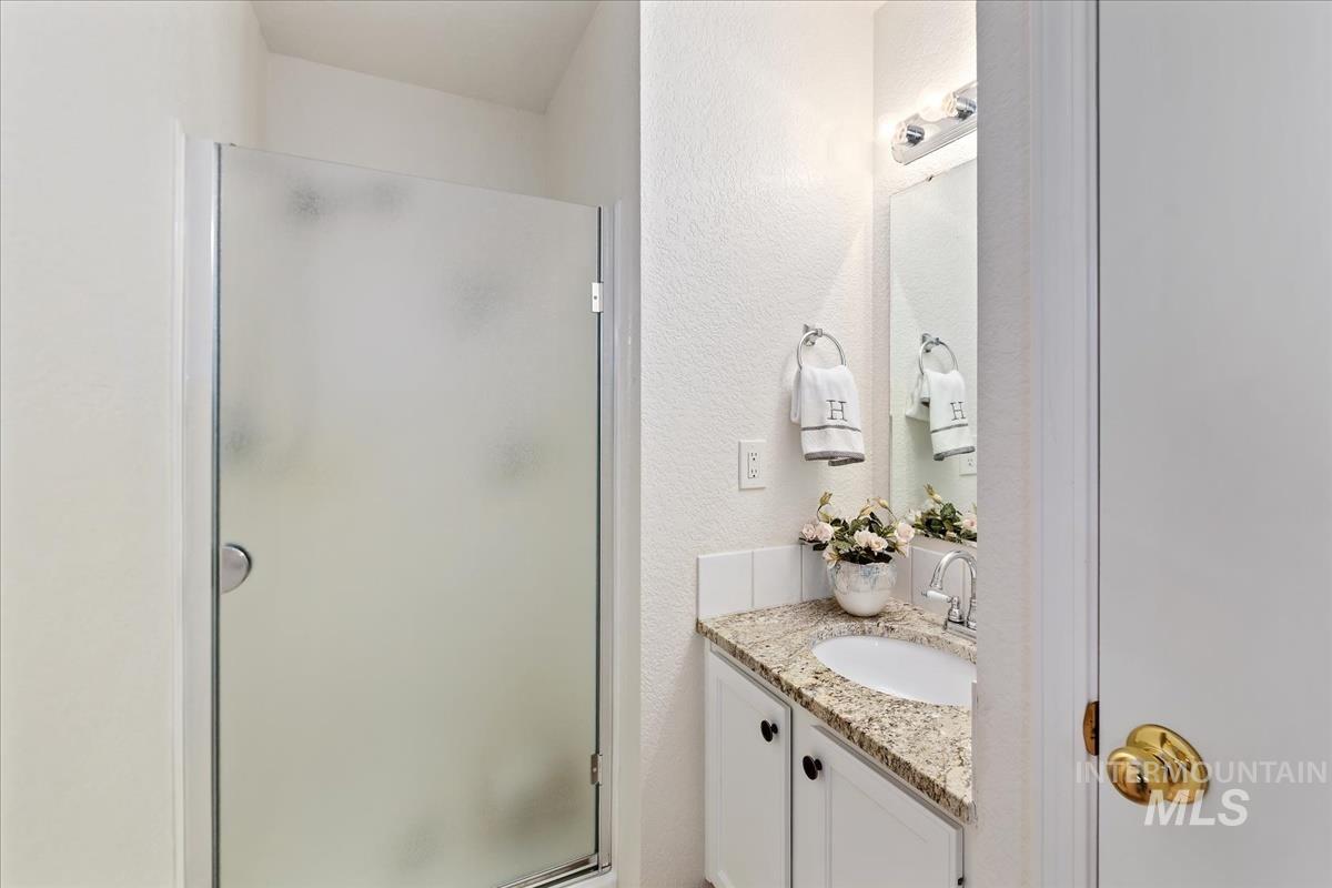 Bathroom with vanity, a stall shower, and a textured wall