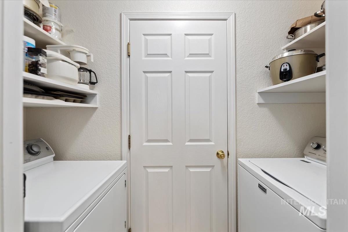 Washroom with a textured wall and washer and clothes dryer