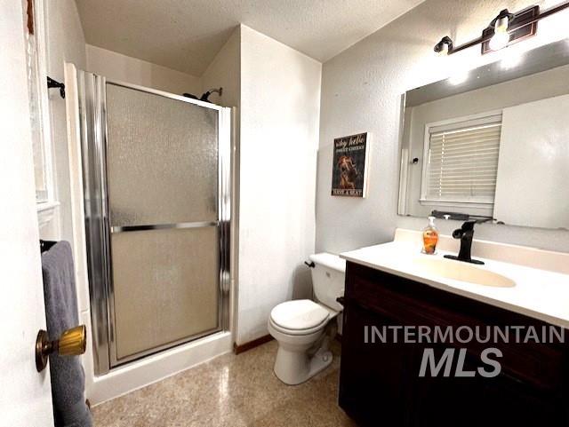 Bathroom featuring vanity, a stall shower, and a textured ceiling