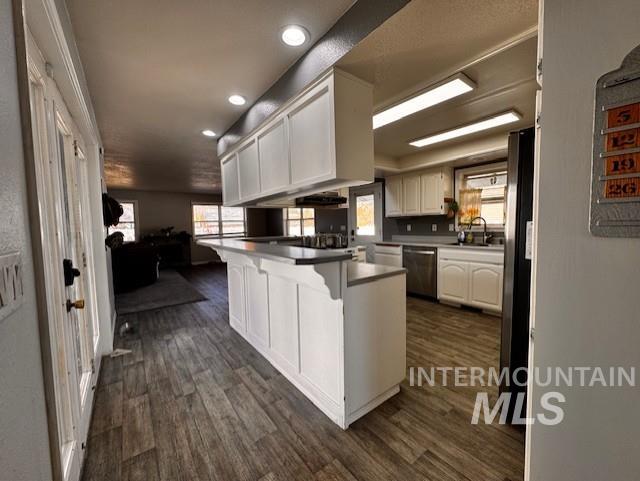 Kitchen featuring white cabinetry, a kitchen breakfast bar, dark wood finished floors, recessed lighting, and appliances with stainless steel finishes