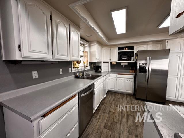 Kitchen with white cabinetry, a tray ceiling, stainless steel appliances, and dark wood-type flooring