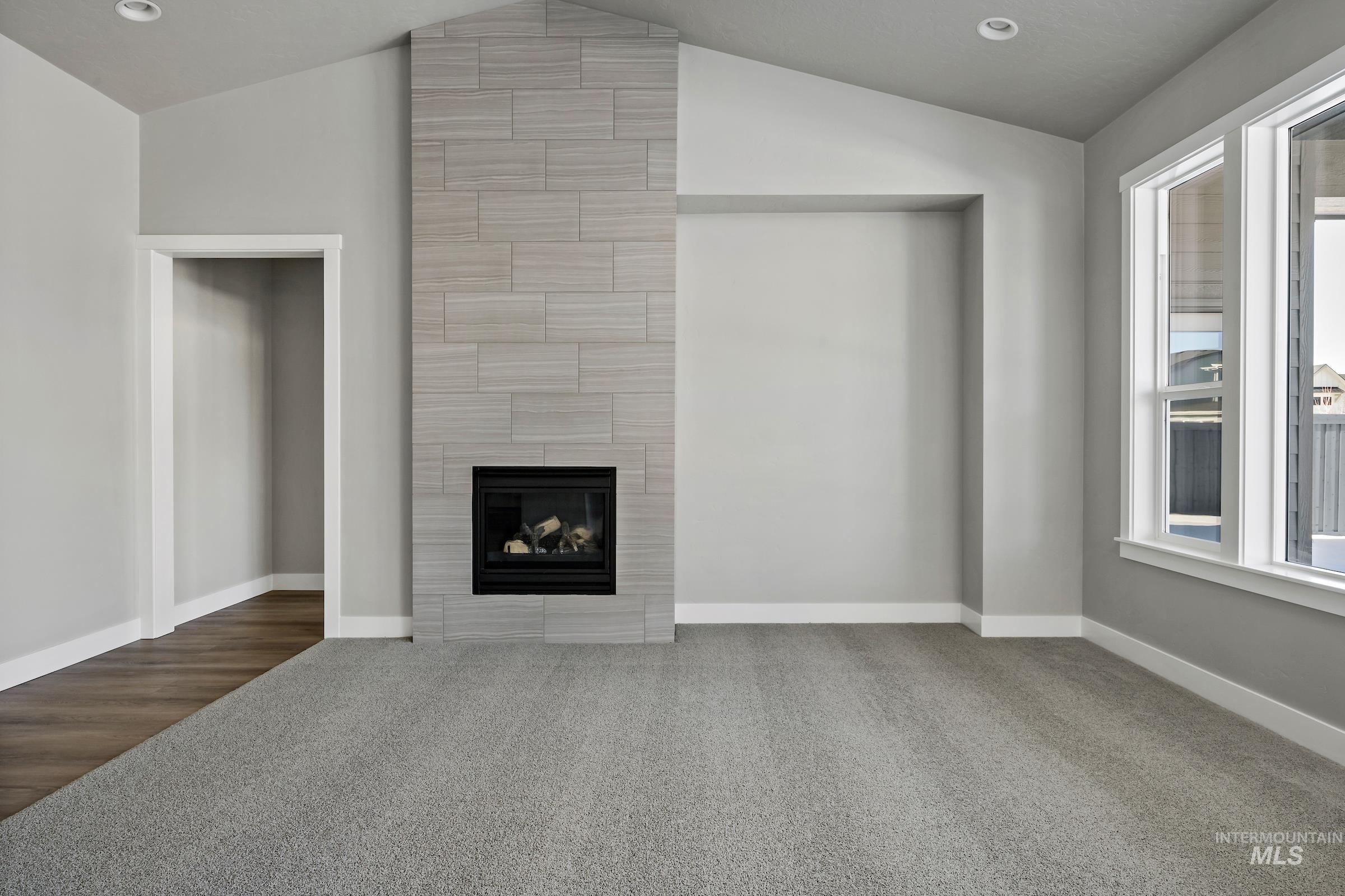 Unfurnished living room featuring carpet floors, recessed lighting, a fireplace, and vaulted ceiling