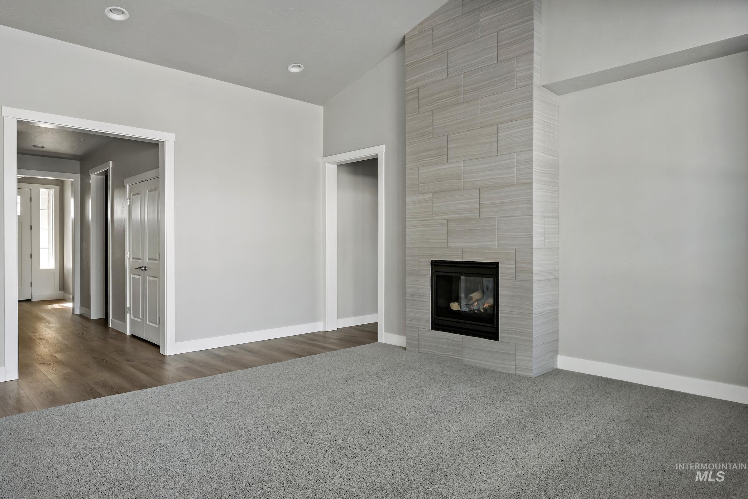 Unfurnished living room featuring carpet flooring, a fireplace, recessed lighting, and lofted ceiling