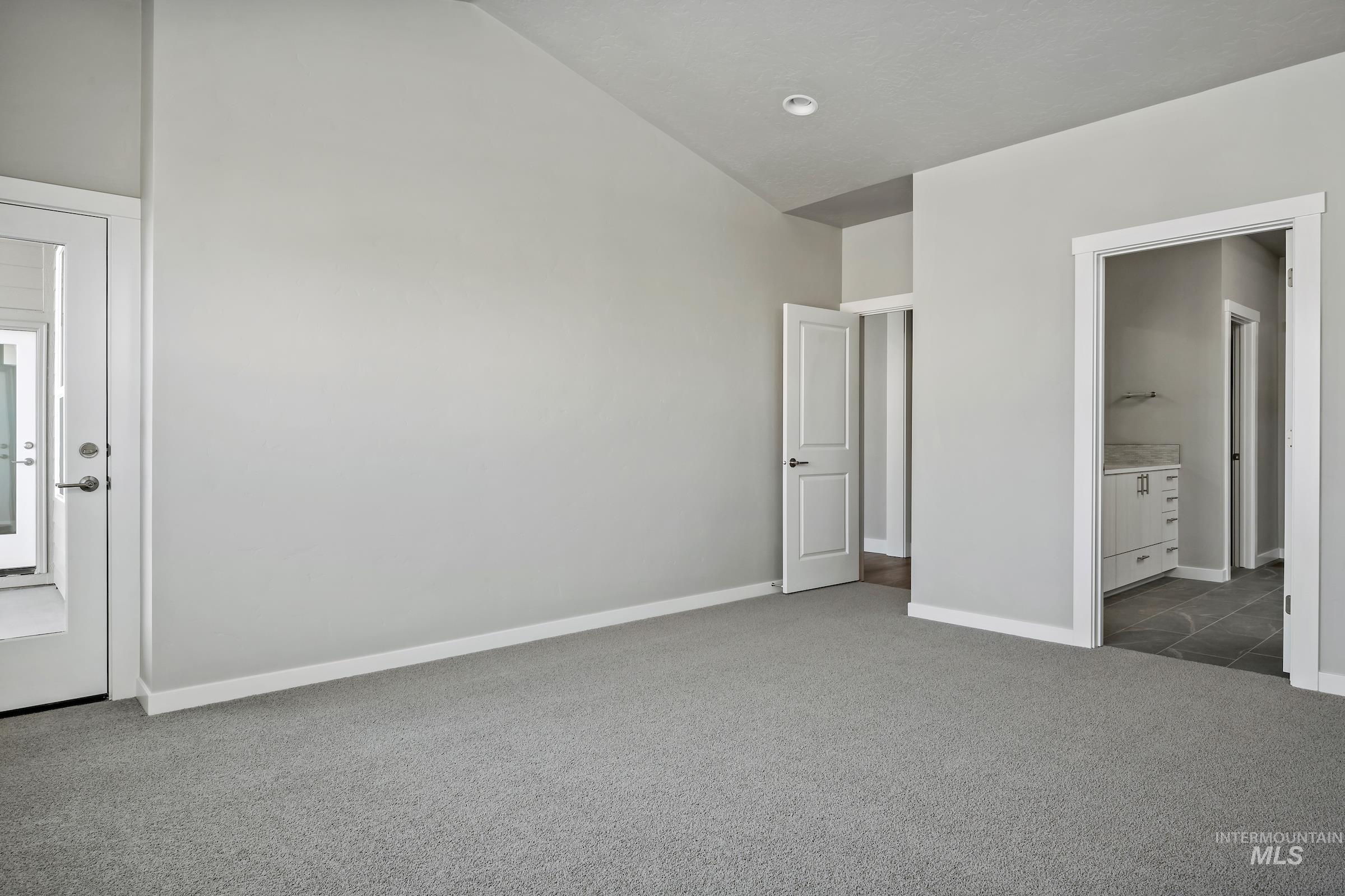 Unfurnished bedroom featuring carpet floors, connected bathroom, and high vaulted ceiling